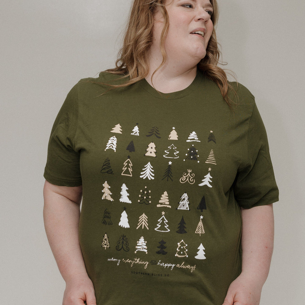 Person wearing an olive green t-shirt with tree patterns on a plain background