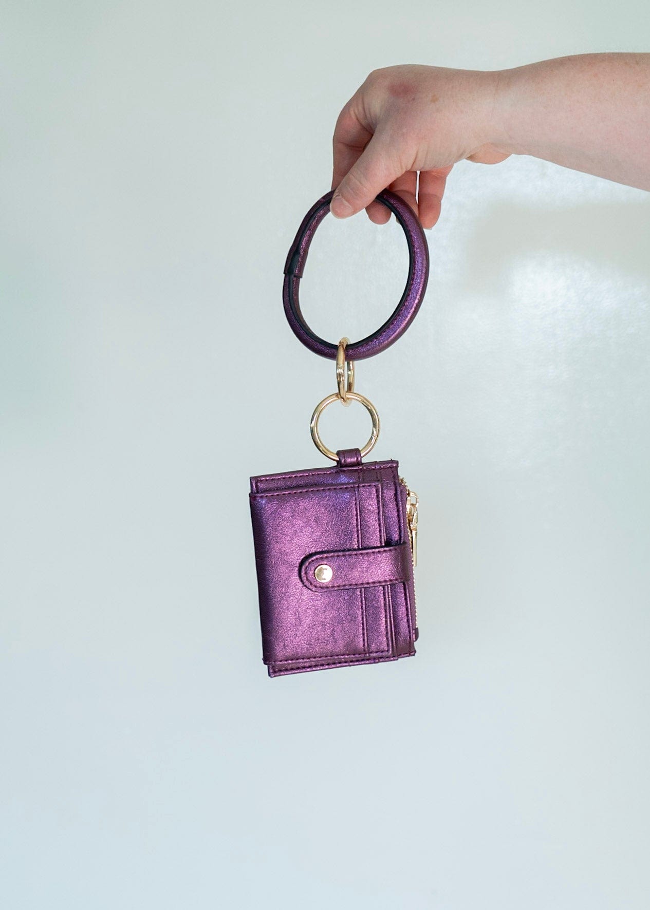 Show off your style with this metallic bangle wristlet wallet. Fold out the wallet to access your cards and IDs in secure snap closure — saving you from the rummage. Zip up your change pocket for a chic, sophisticated finish. Throw it on your wrist for easy access with an amethyst accent!