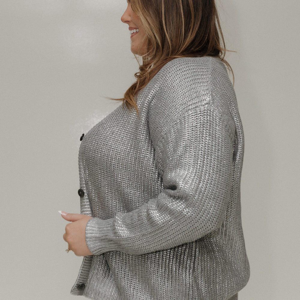 Woman wearing a silver textured cardigan against a plain background