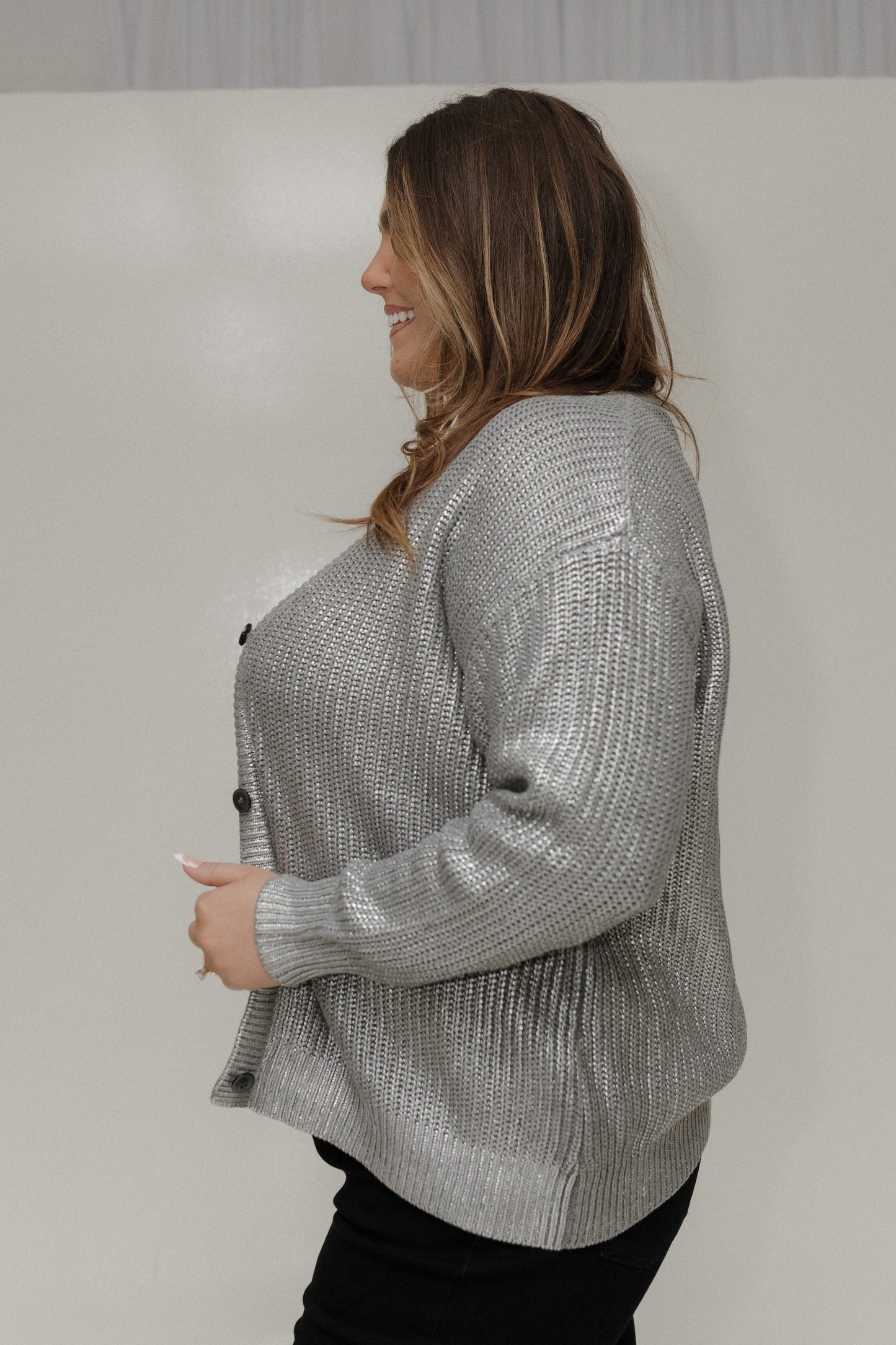 Woman wearing a silver textured cardigan against a plain background