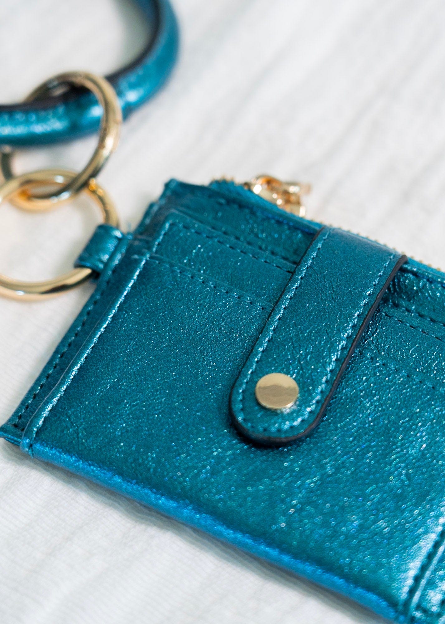 Make a bold statement with this METALLIC BANGLE WRISTLET WALLET IN MALACHITE! Its fold-out wallet design, snap closure, card slots, and zip change pocket provide all the functionality you need for running around town. Who says you can't look stylish while staying organized? This wallet does it all!