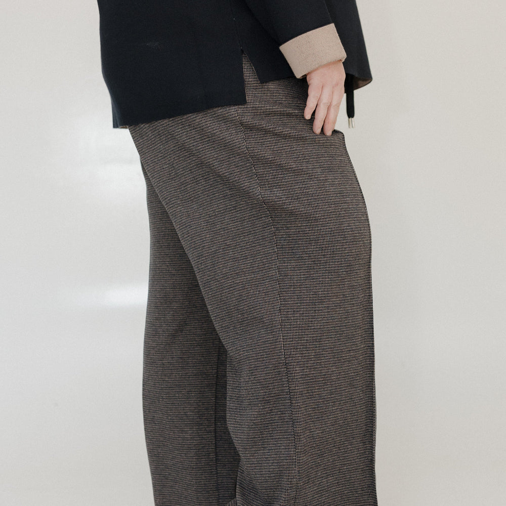 Person wearing a black coat and gray checkered pants on a white background
