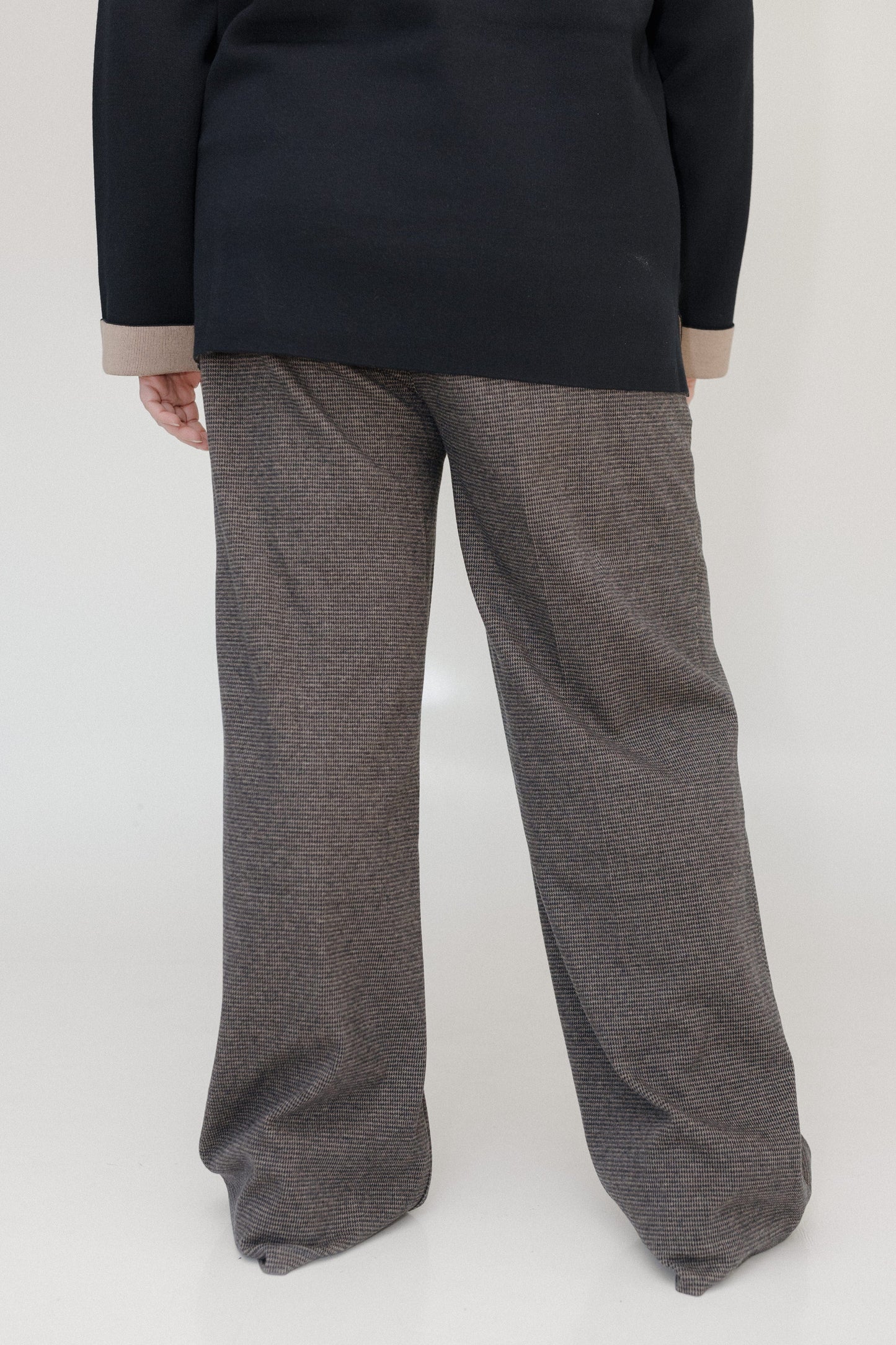 Person wearing a black top and gray pants on a white background