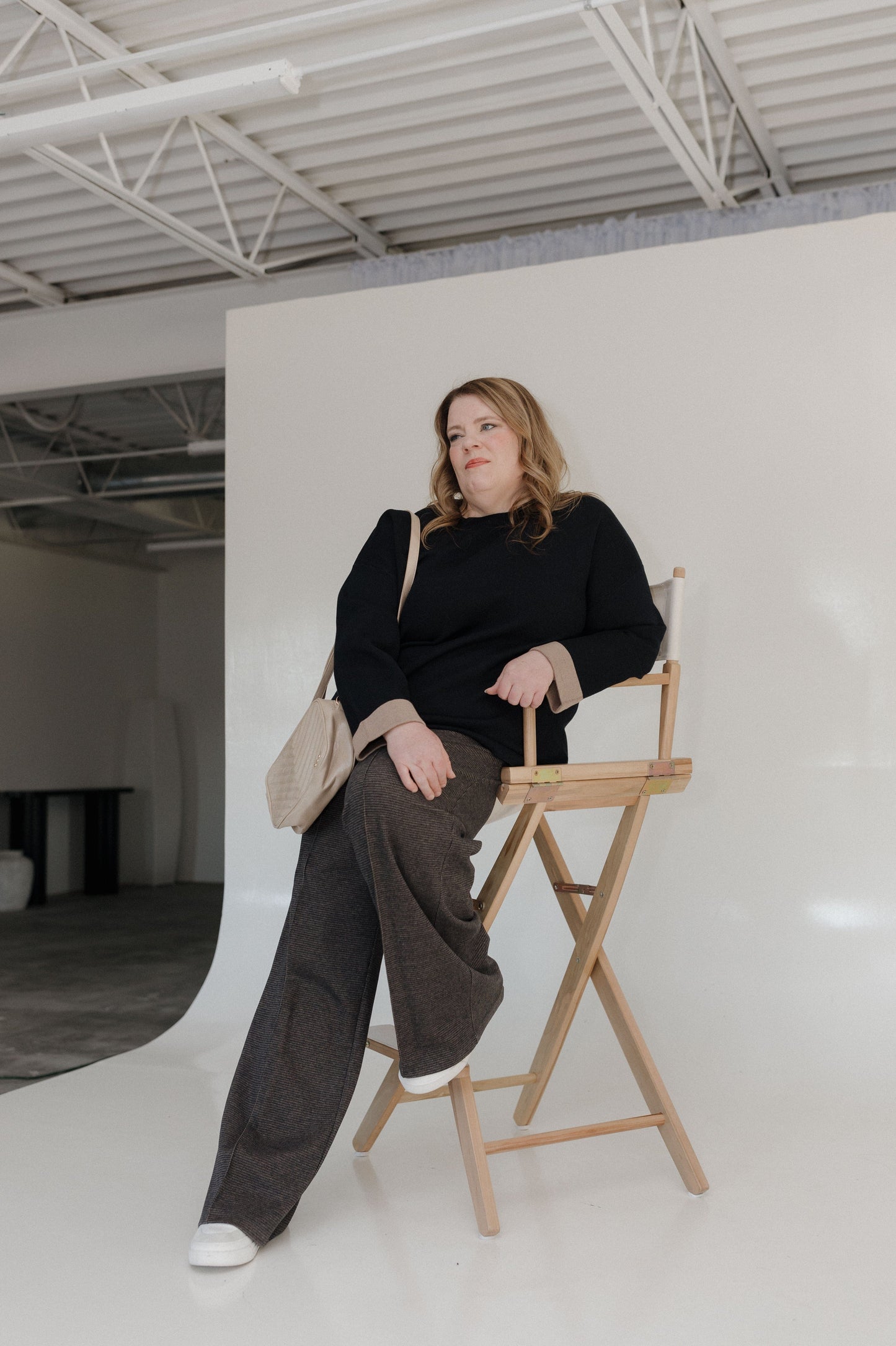 Woman sitting on a director's chair in a minimalistic studio setting