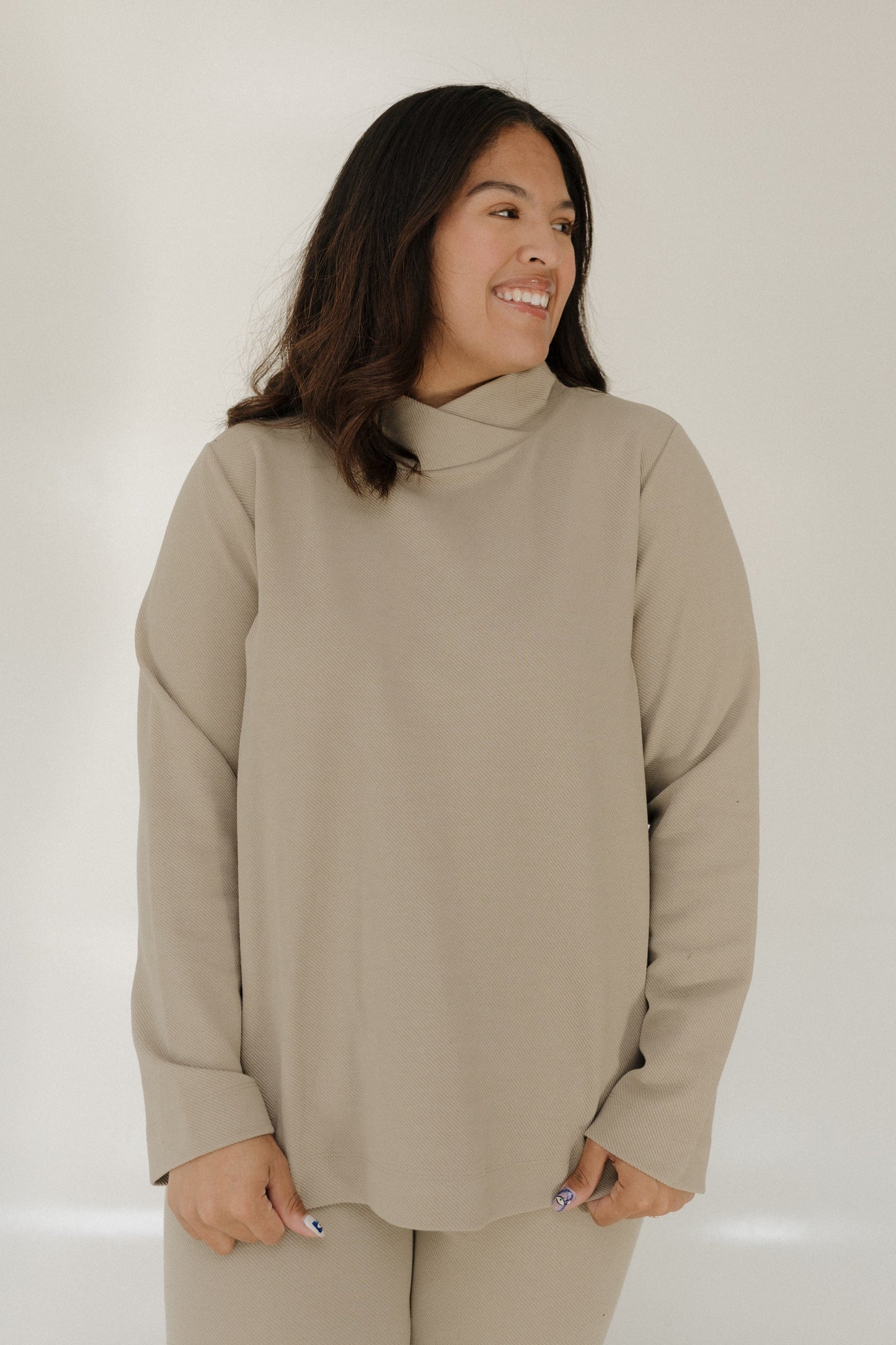Woman wearing a beige turtleneck sweater against a white background