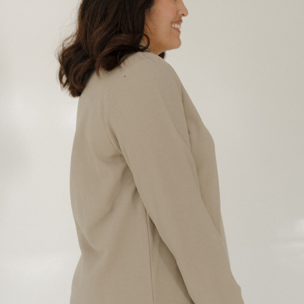 Woman wearing a beige blazer against a white background