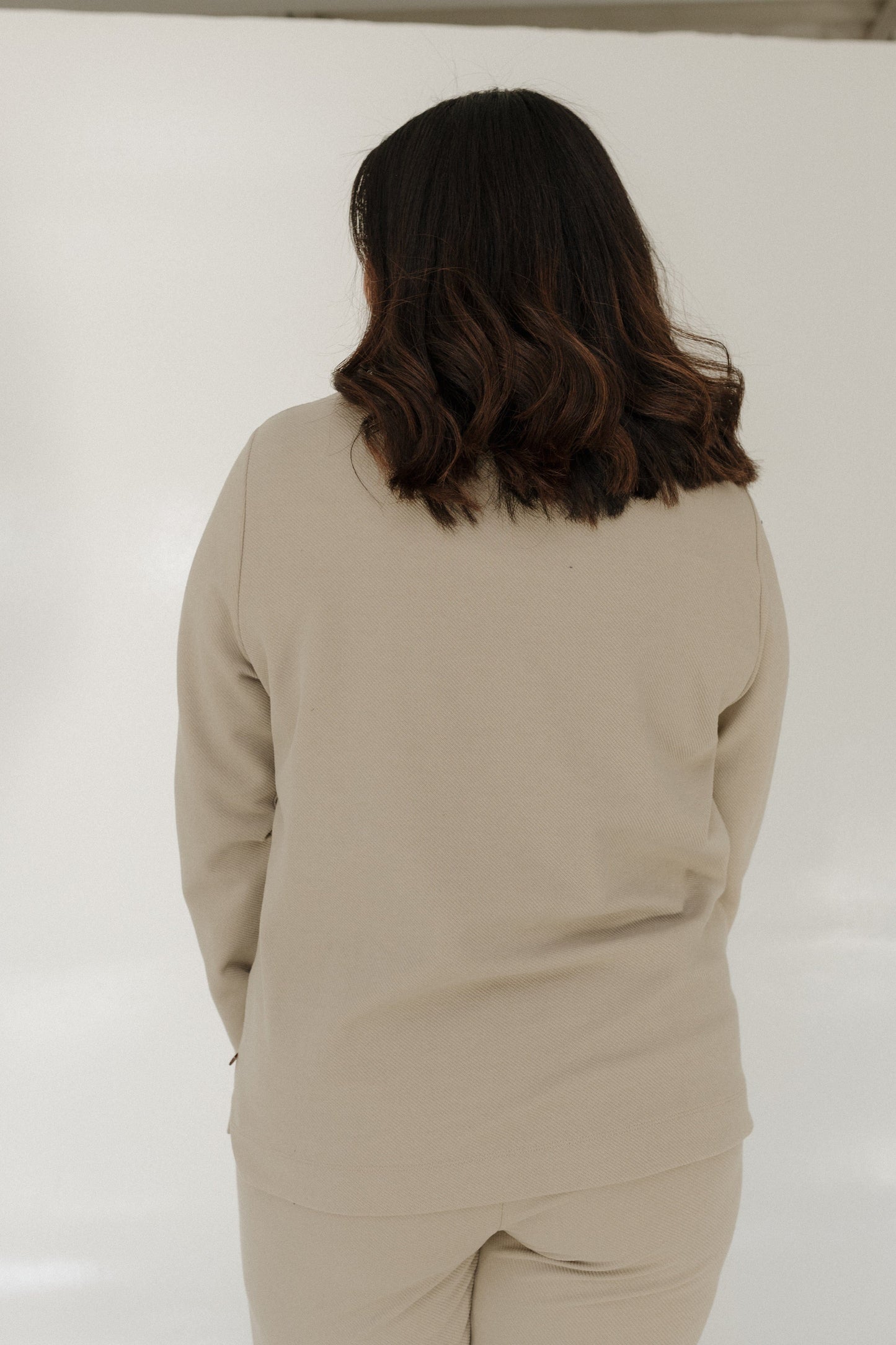 Person wearing a beige outfit against a white background