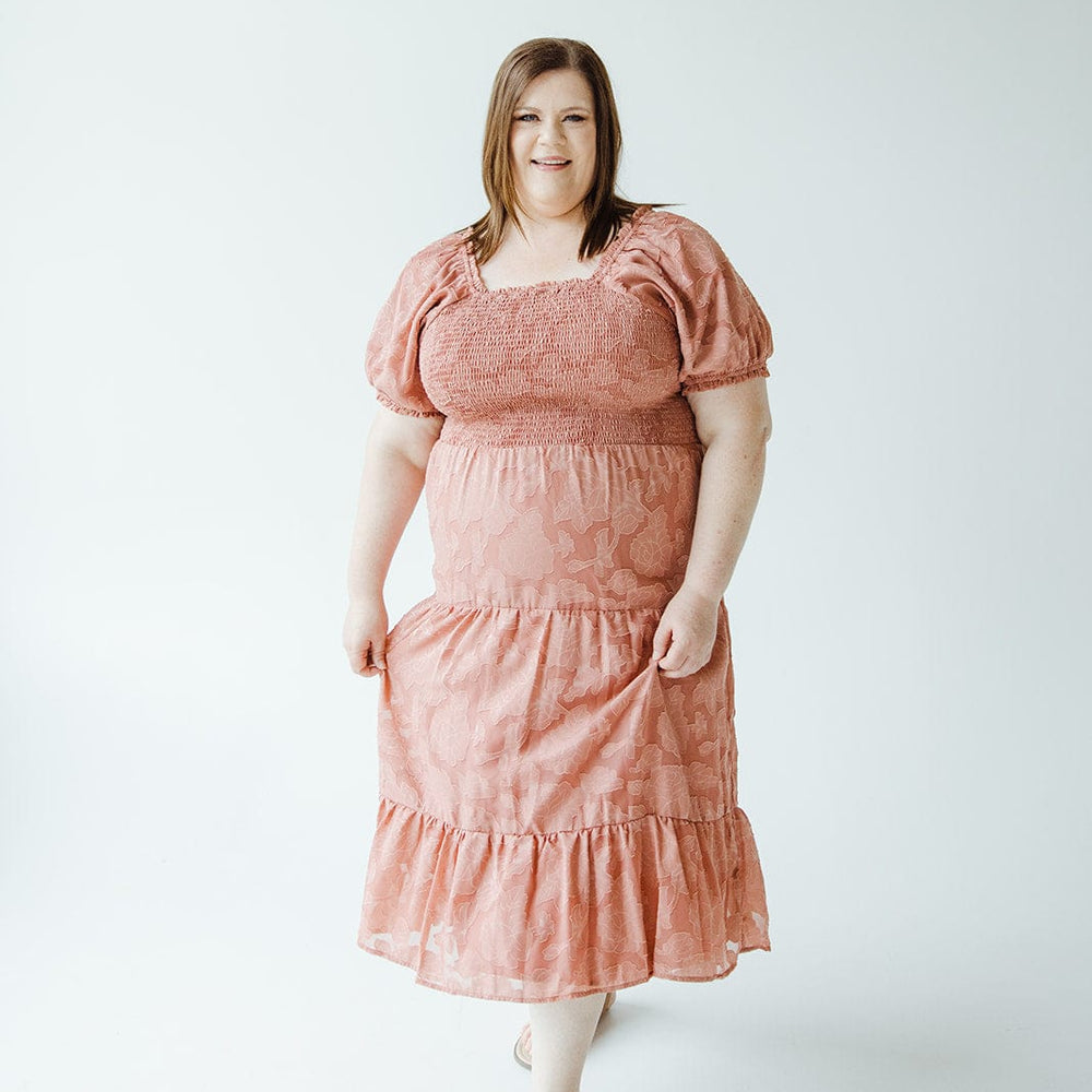 A woman wearing a MIDI-LENGTH LACE APPLIQUES IN PRESSED FLOWER dress by Mikarose stands against a plain white background.