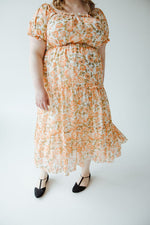 A person with long hair in a Mikarose MIDI-LENGTH FLORAL DRESS WITH BUBBLE SLEEVE stands facing away from the camera against a plain, light-colored background.