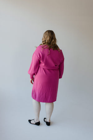 A woman dressed in a MIDI LENGTH SWEATER DRESS by Yesta, featuring bubble sleeves in a fuchsia rose hue.