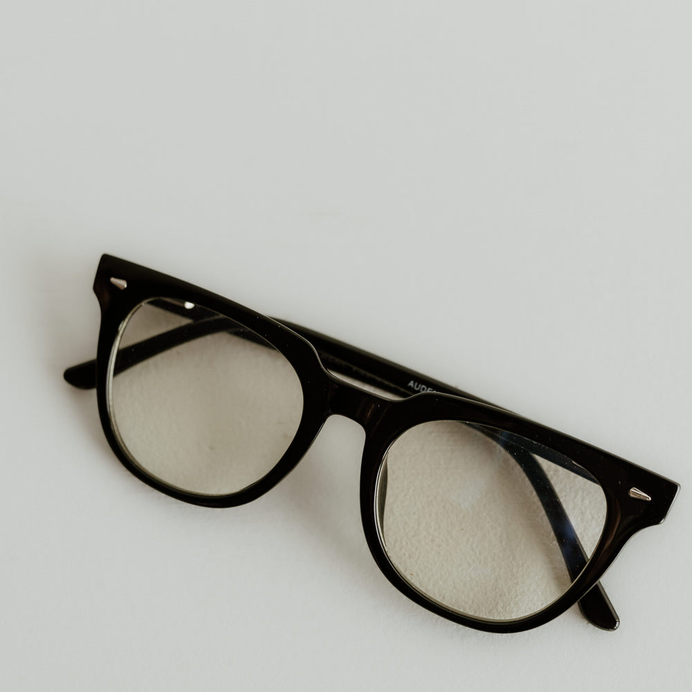 Black-framed eyeglasses on a light gray background