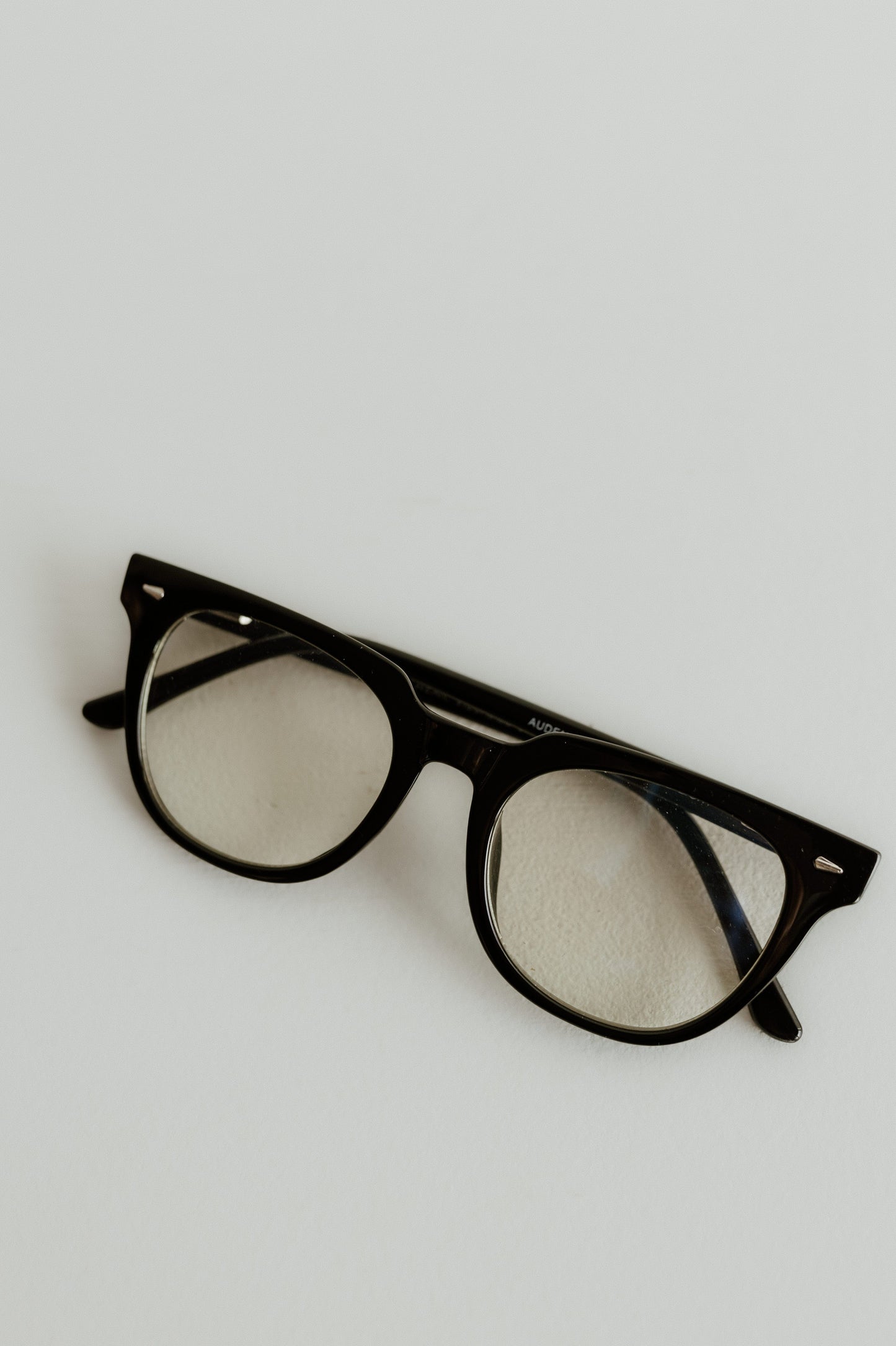 Black-framed eyeglasses on a light gray background