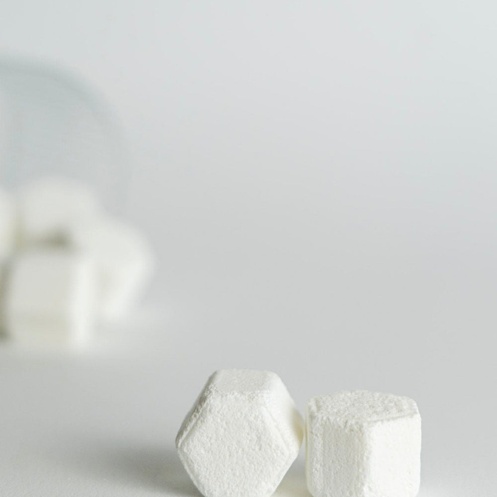 Two white hexagonal shower steamers on a light gray background