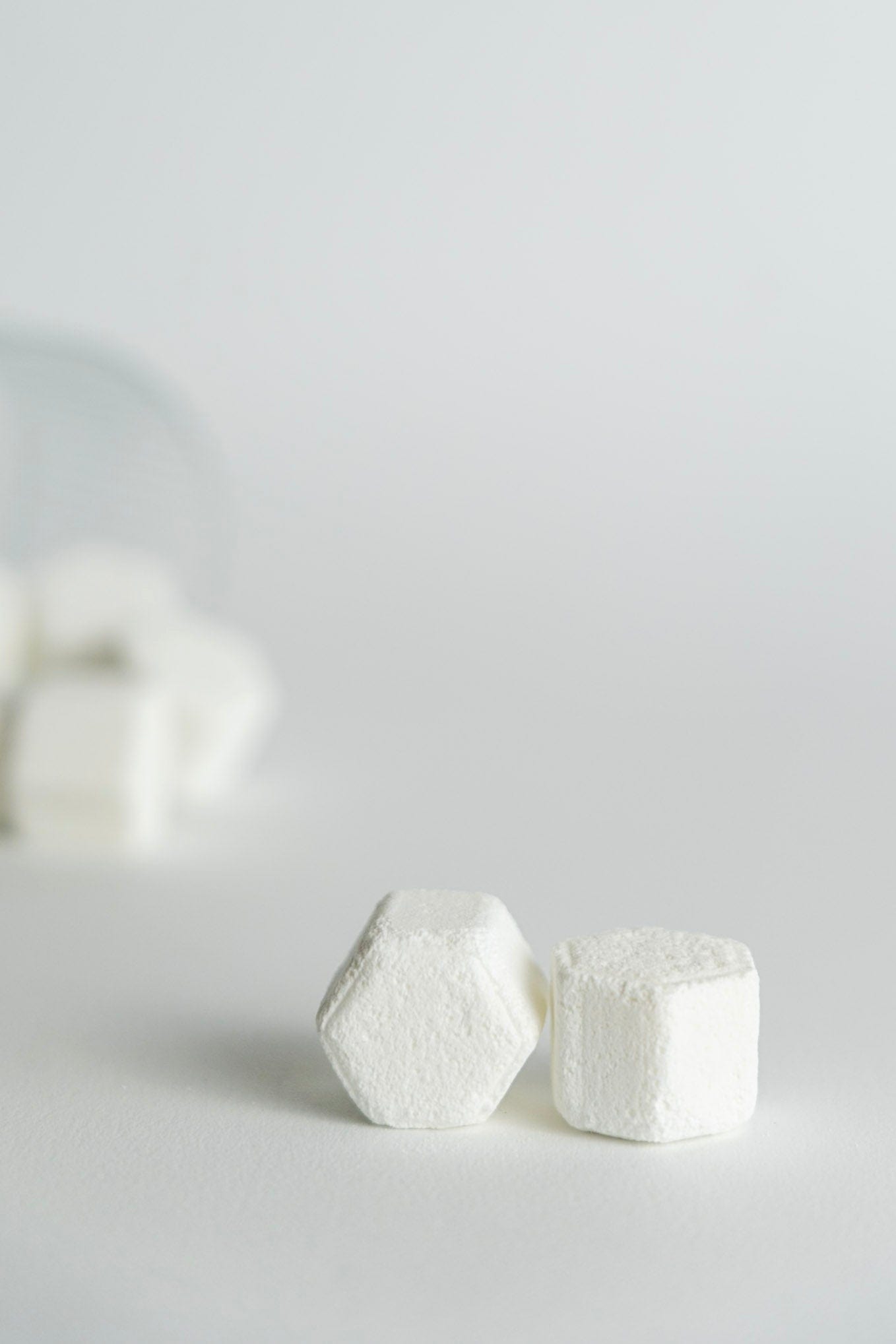 Two white hexagonal shower steamers on a light gray background