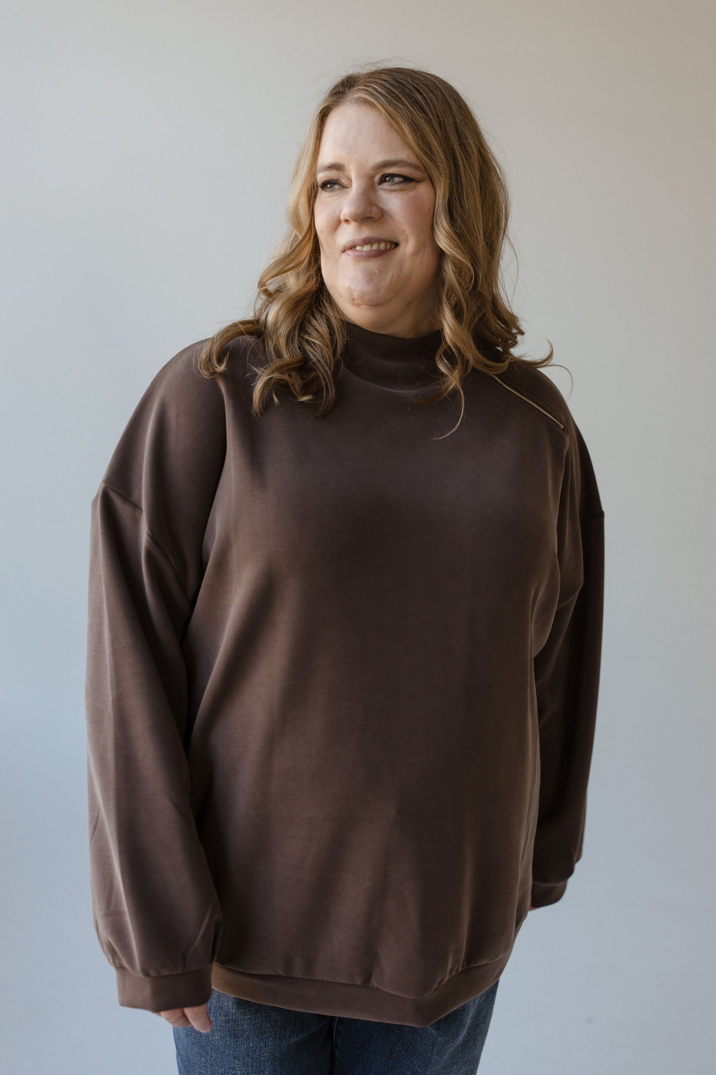 A person wearing the Yesta Mock Turtleneck Zipper Detail Blouse stands in front of a plain background, effortlessly paired with jeans.