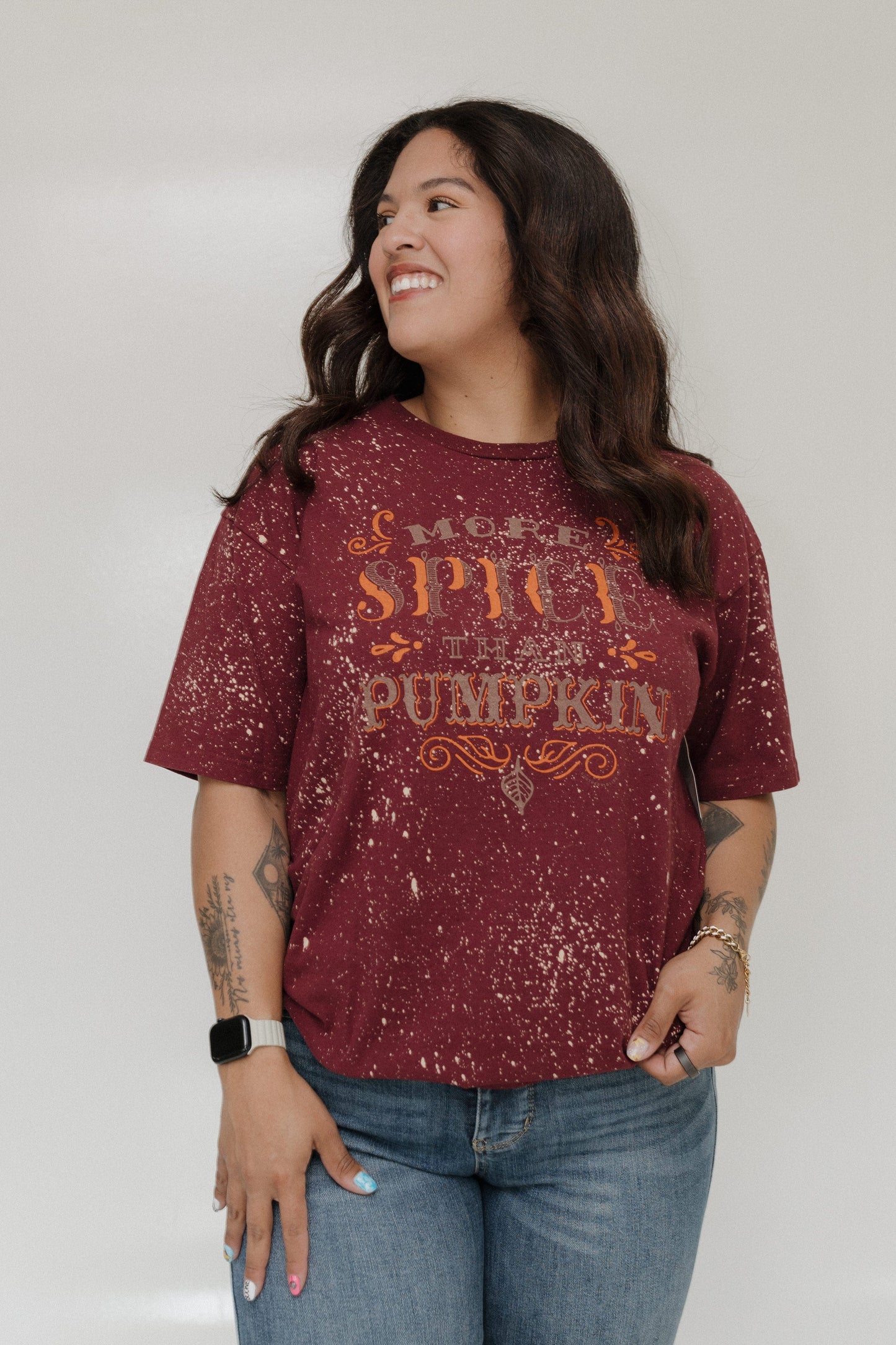 "MORE SPICE THAN PUMPKIN" GRAPHIC TEE Woman wearing a maroon shirt with 'More Spice Than Pumpkin' text on a plain background at Love Marlow