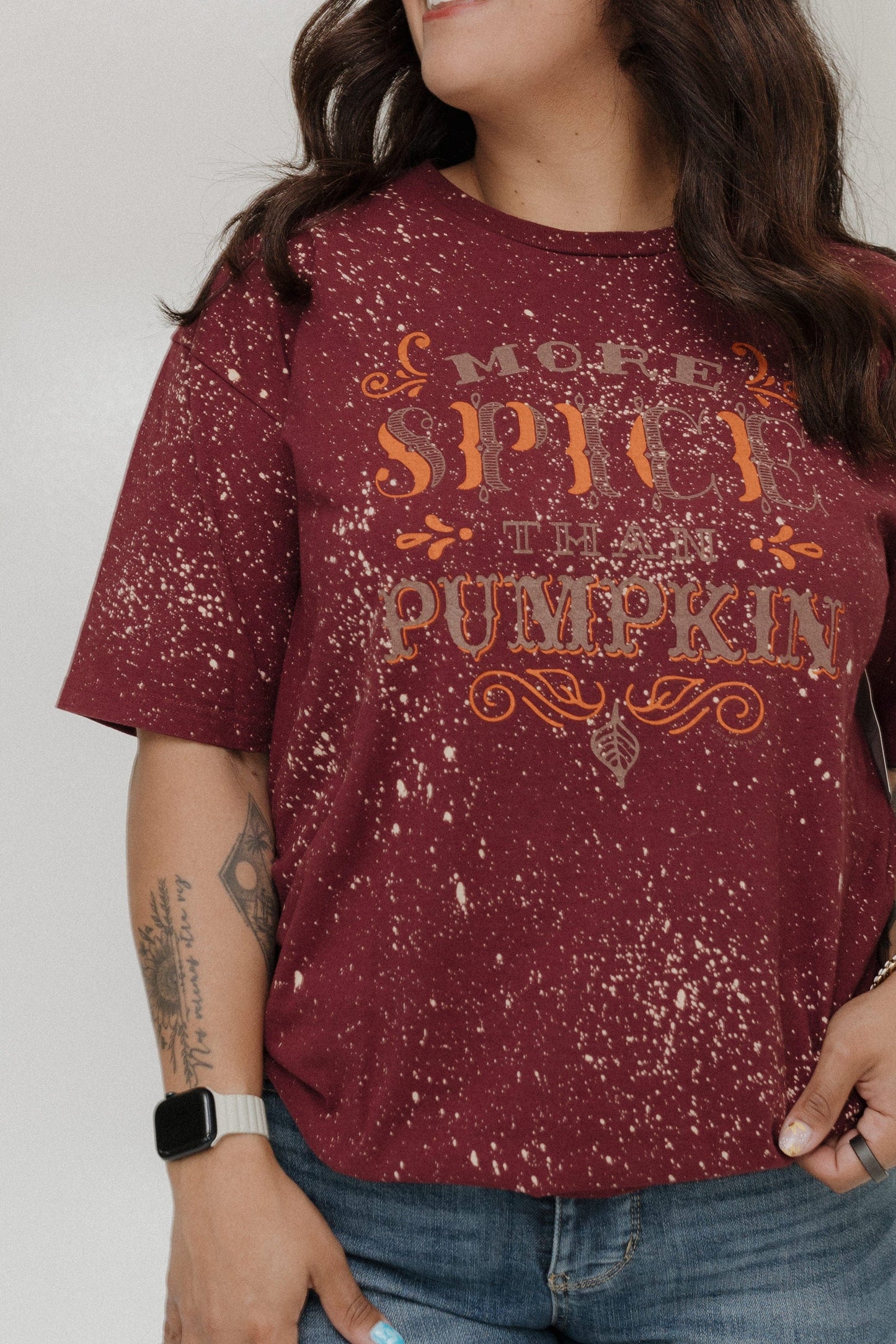 "MORE SPICE THAN PUMPKIN" GRAPHIC TEE Woman wearing a maroon shirt with 'More Spice Than Pumpkin' text on a plain background at Love Marlow