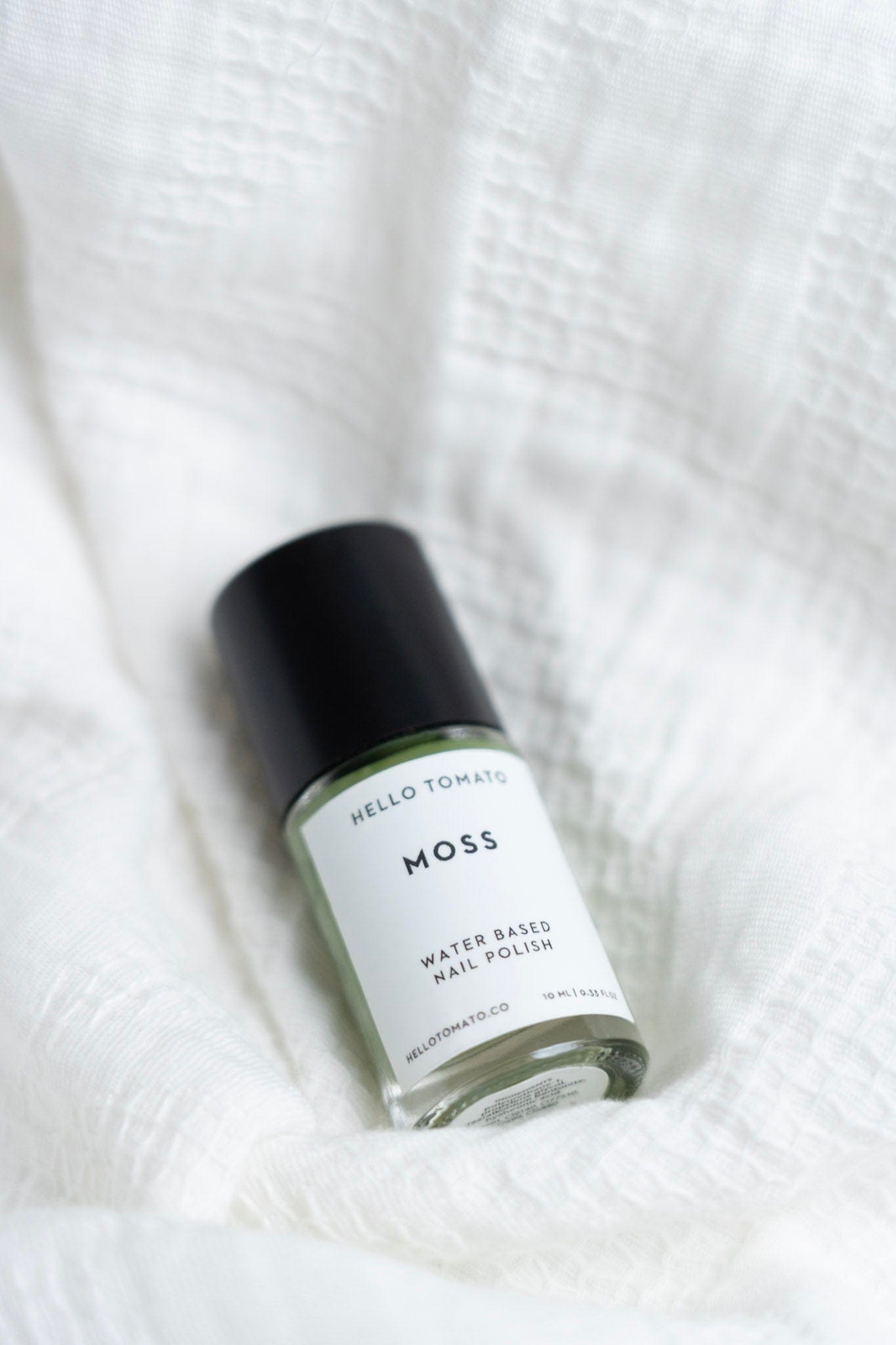 Moss water-based nail polish bottle on a white textured background