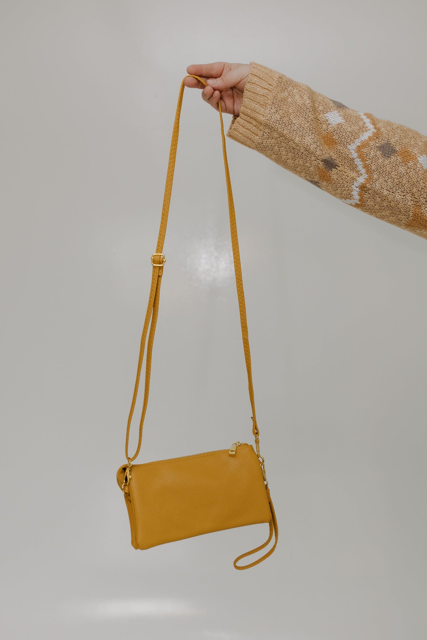 Mustard handbag held by a person against a plain background