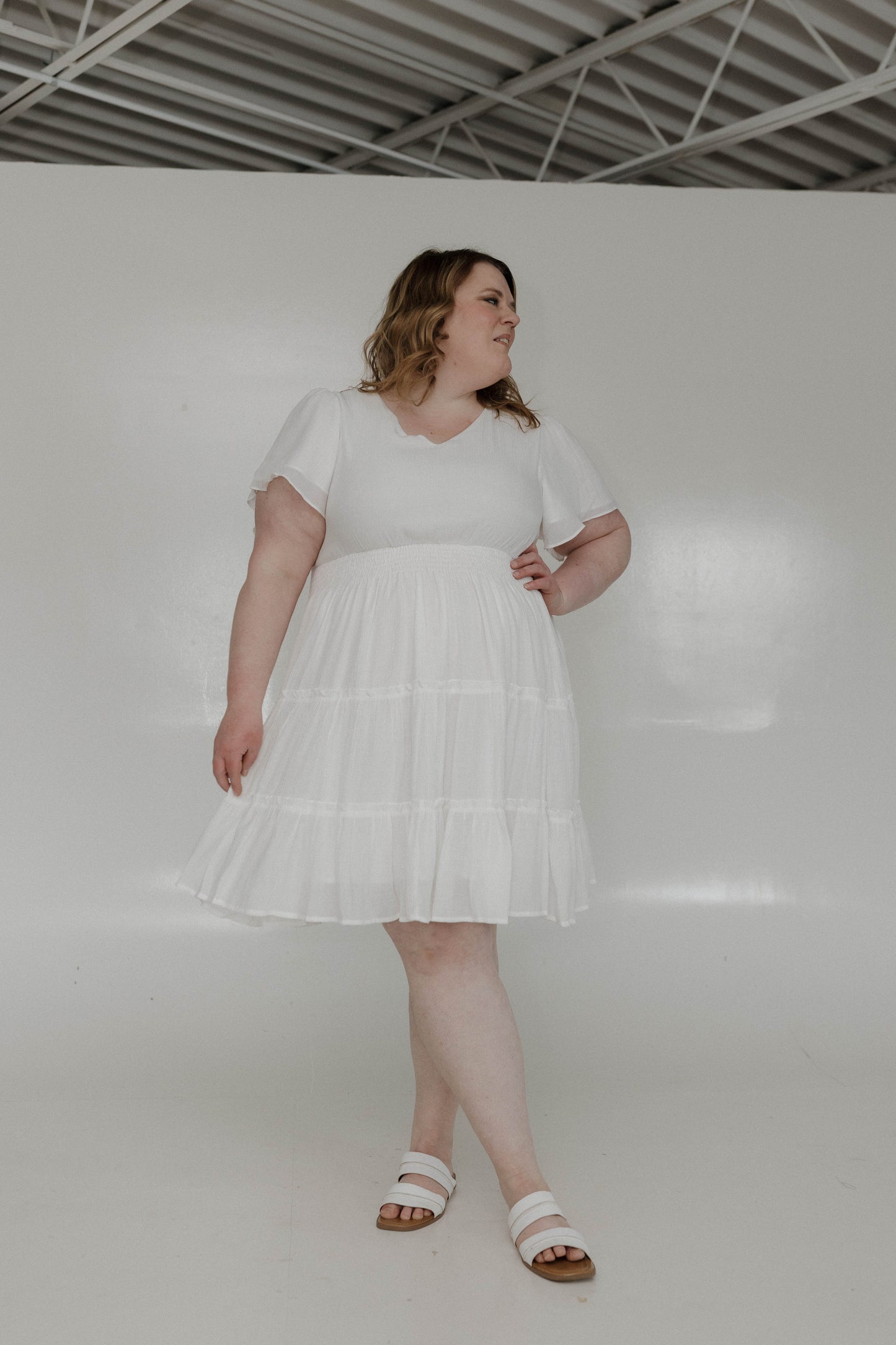 Woman wearing a white dress standing against a plain white background