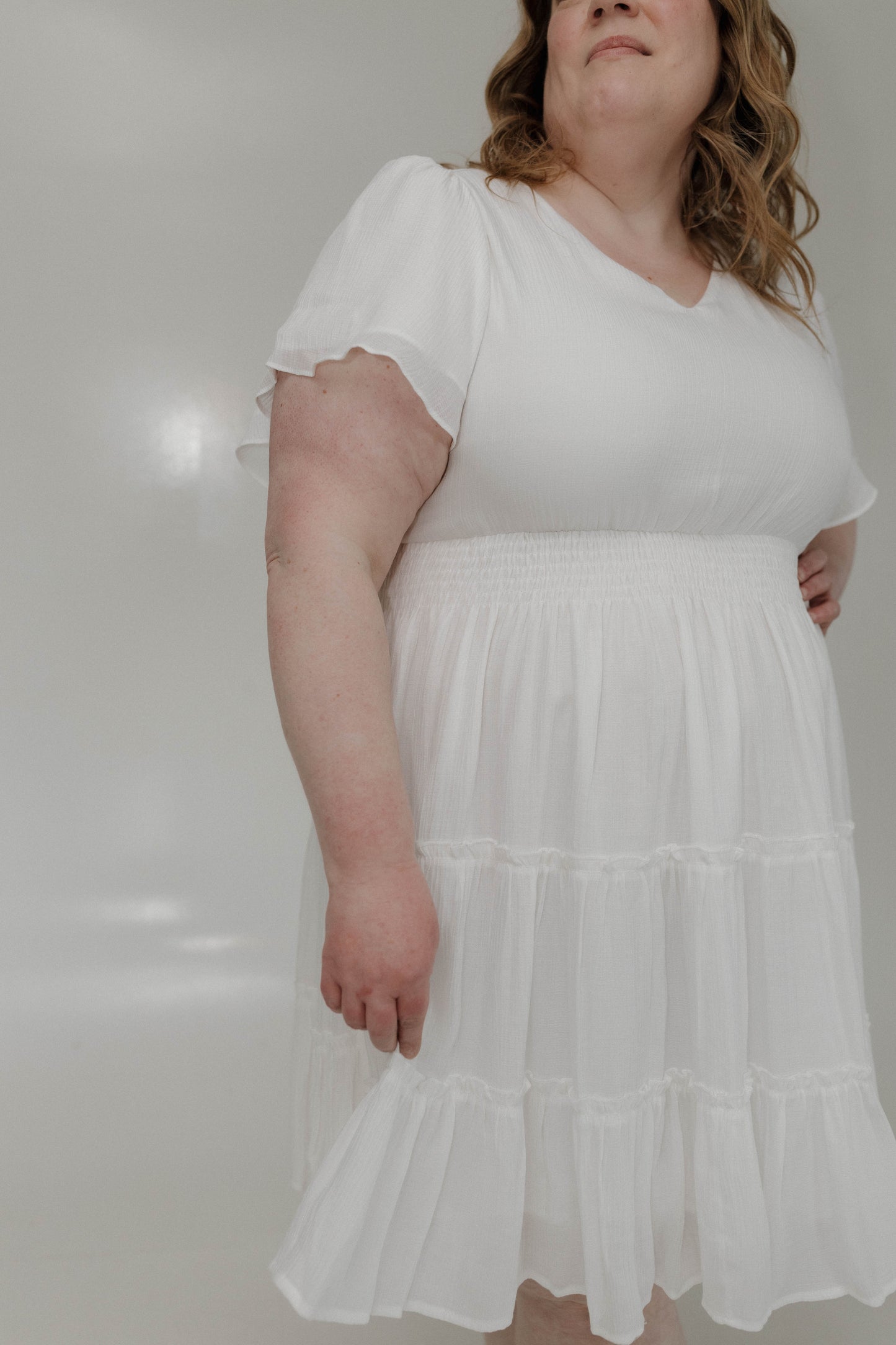 Woman wearing a white dress against a plain background