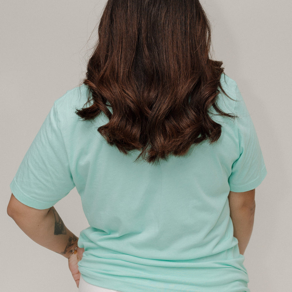 Person wearing a light blue t-shirt and white pants against a plain background