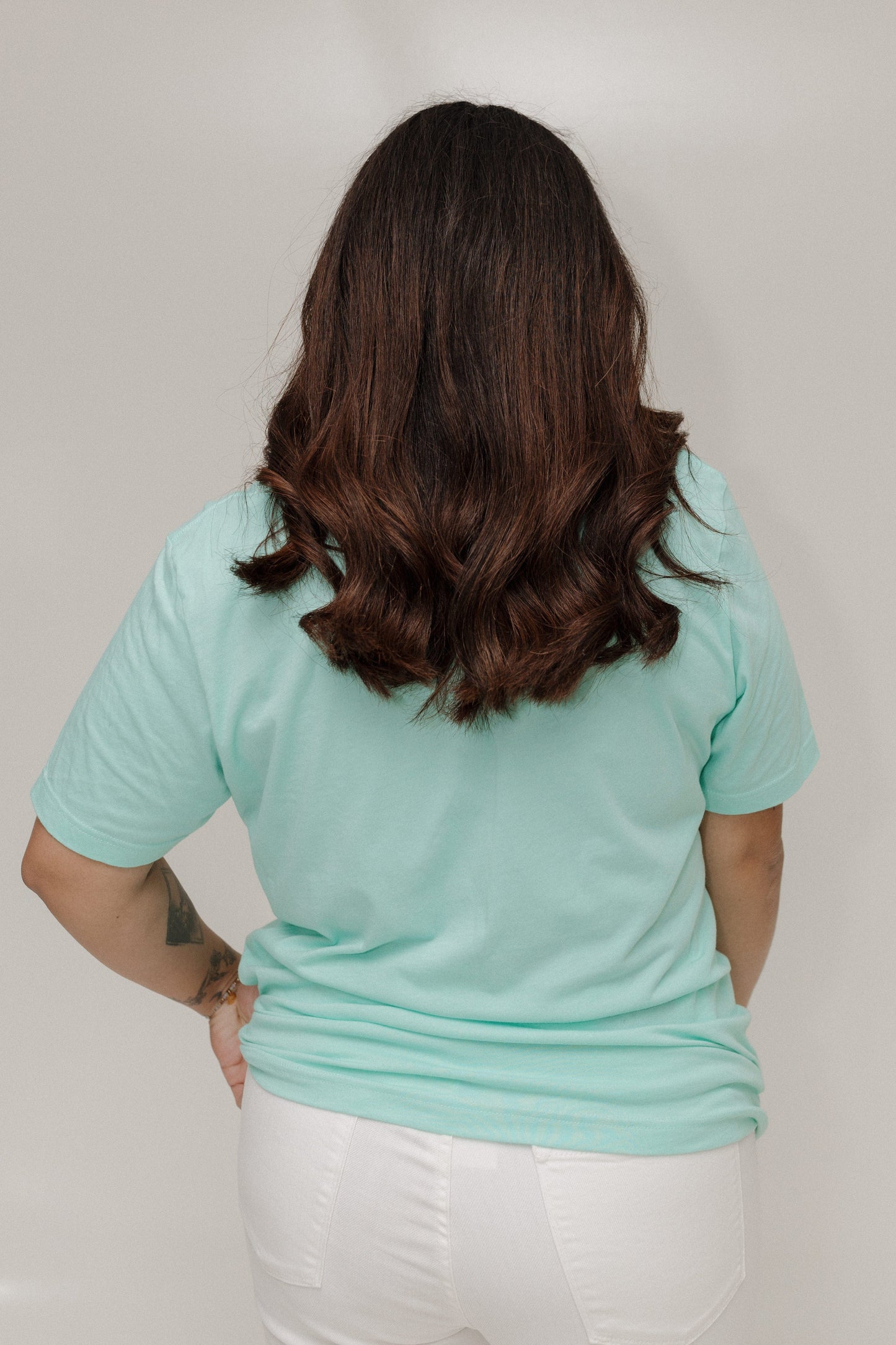Person wearing a light blue t-shirt and white pants against a plain background