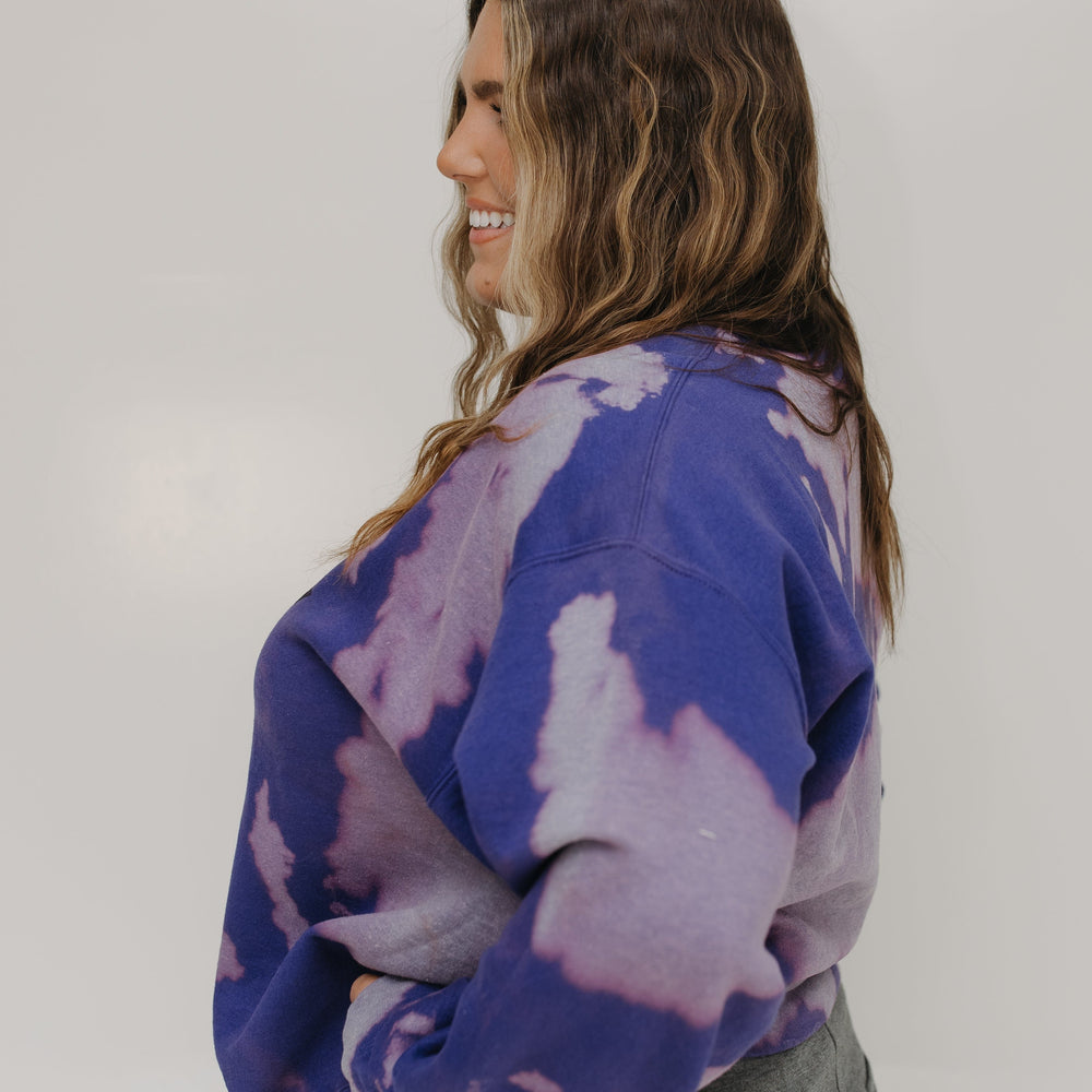 Woman wearing a purple tie-dye sweatshirt against a white background
