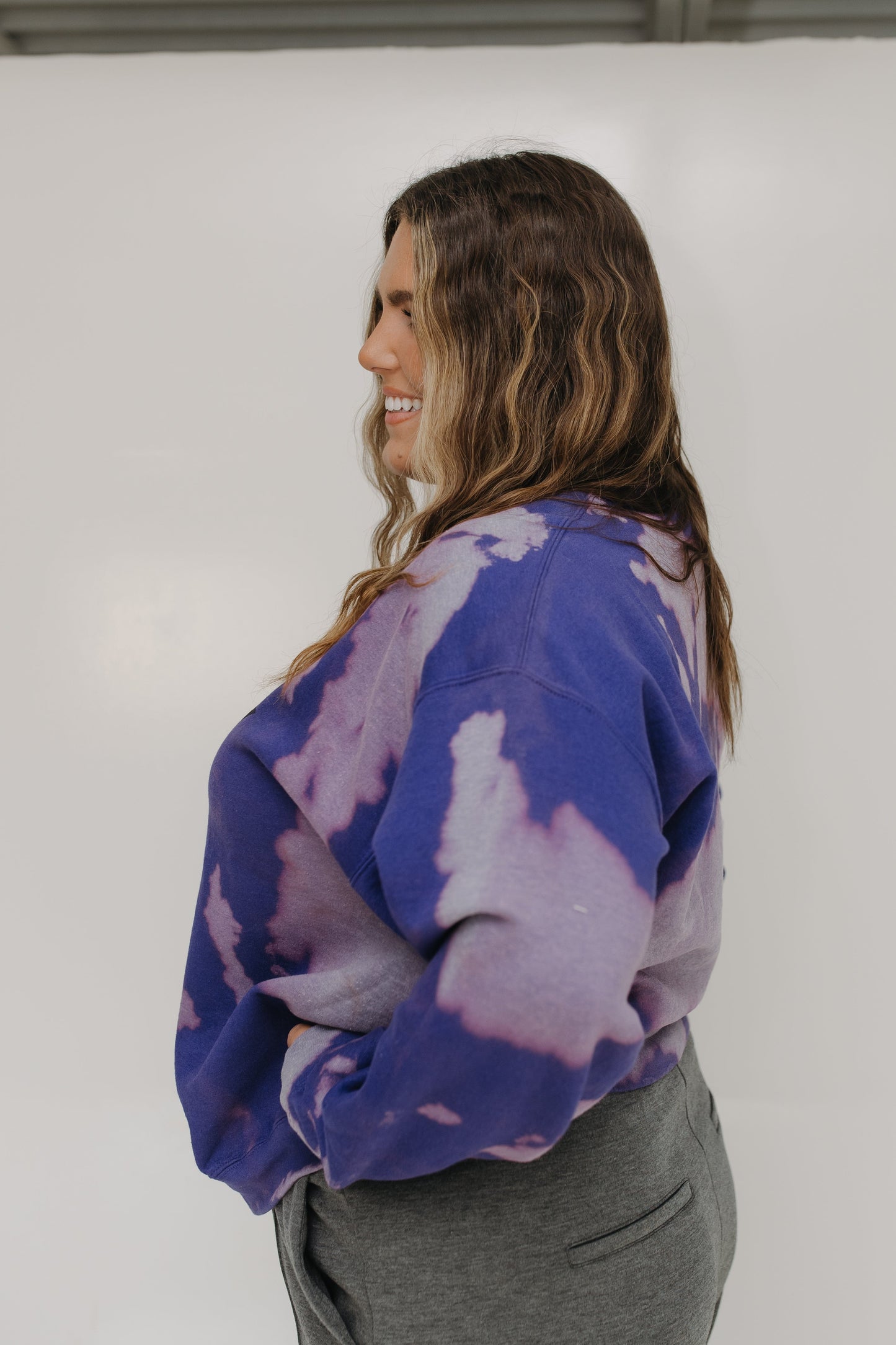 Woman wearing a purple tie-dye sweatshirt against a white background