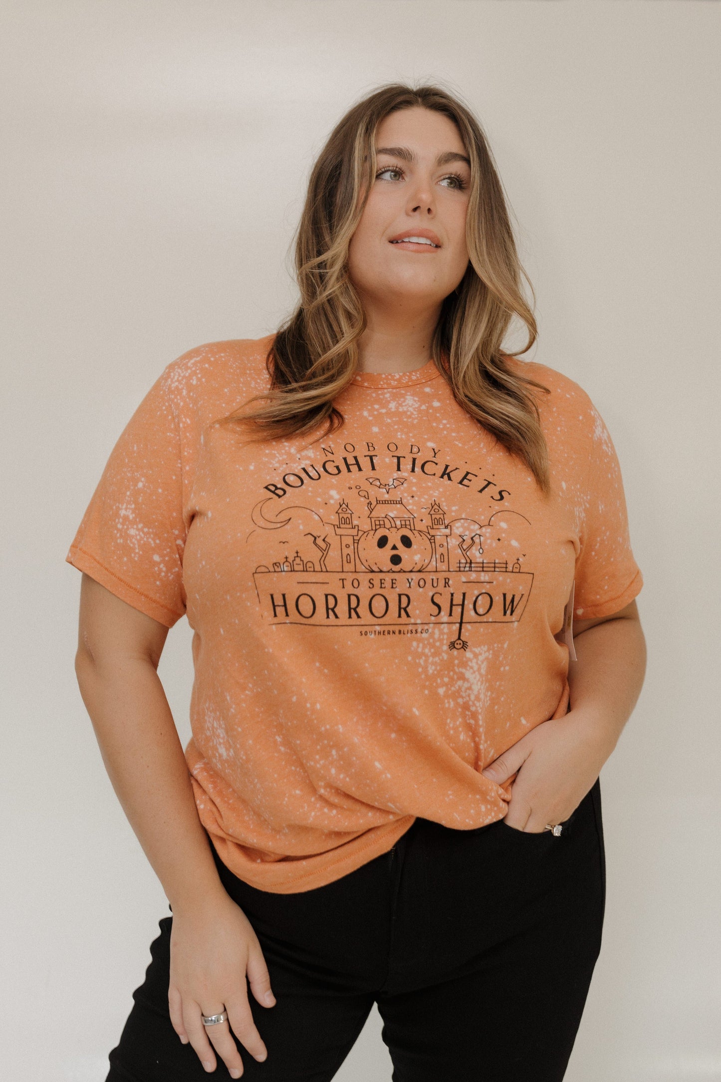 "NOBODY BOUGHT TICKETS TO SEE YOUR HORROR SHOW" GRAPHIC TEE Woman wearing an orange t-shirt with a graphic design at Love Marlow