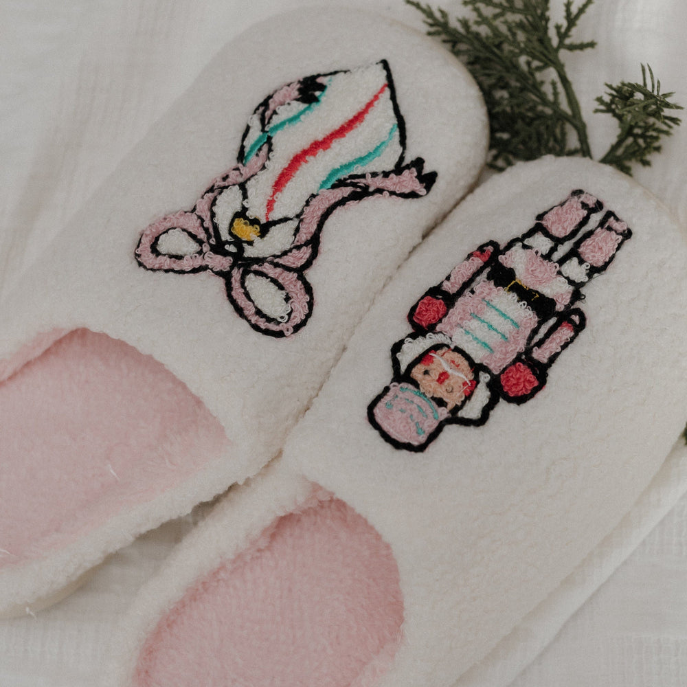 Pair of white slippers with embroidered candy cane design on a light background