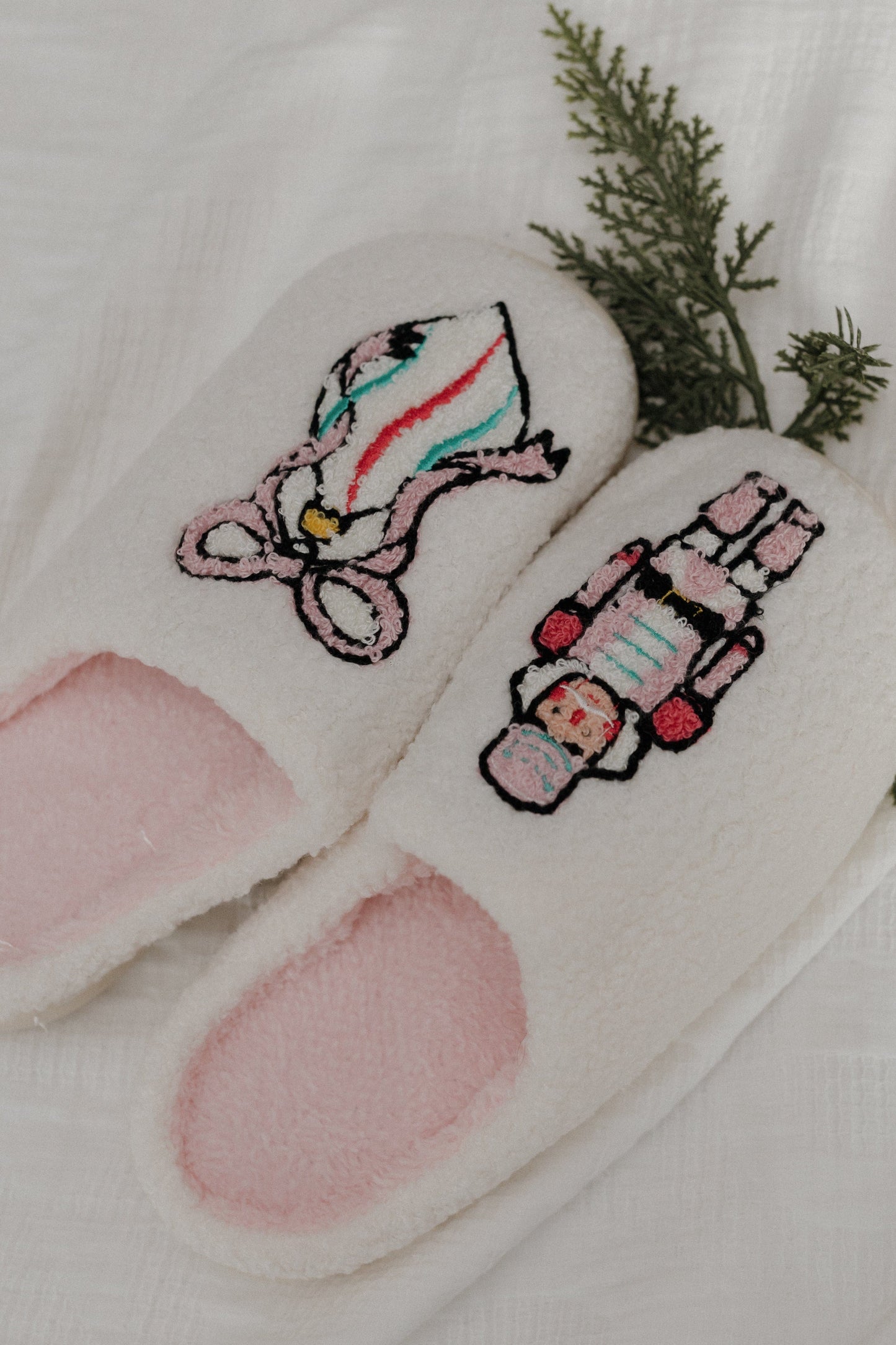 Pair of white slippers with embroidered candy cane design on a light background