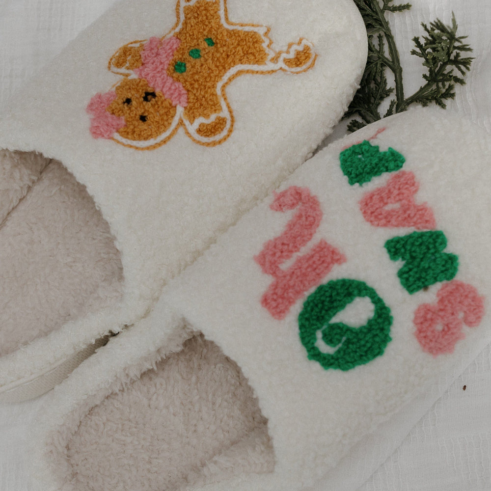Pair of white slippers with festive designs on a light background