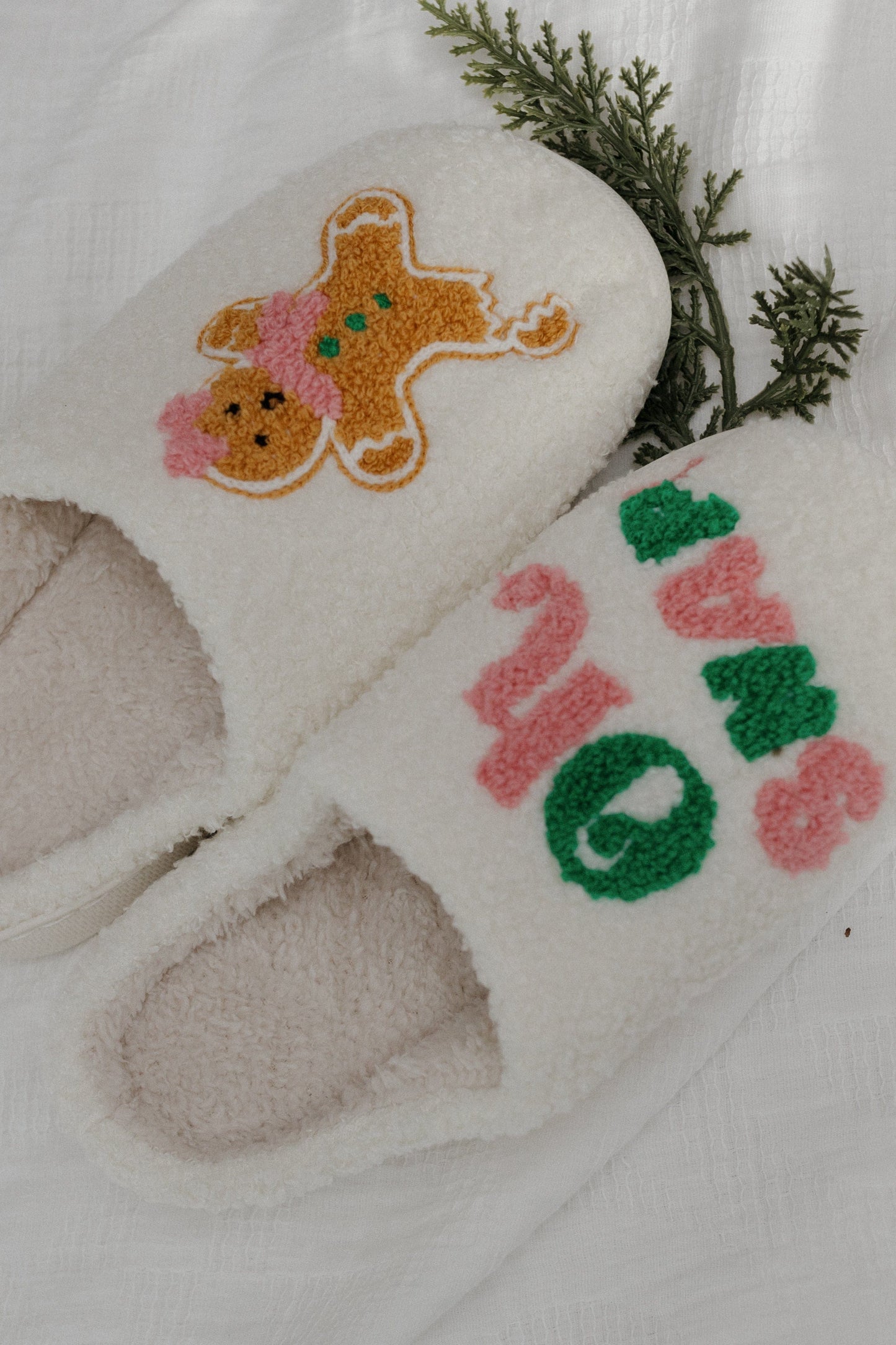 Pair of white slippers with festive designs on a light background