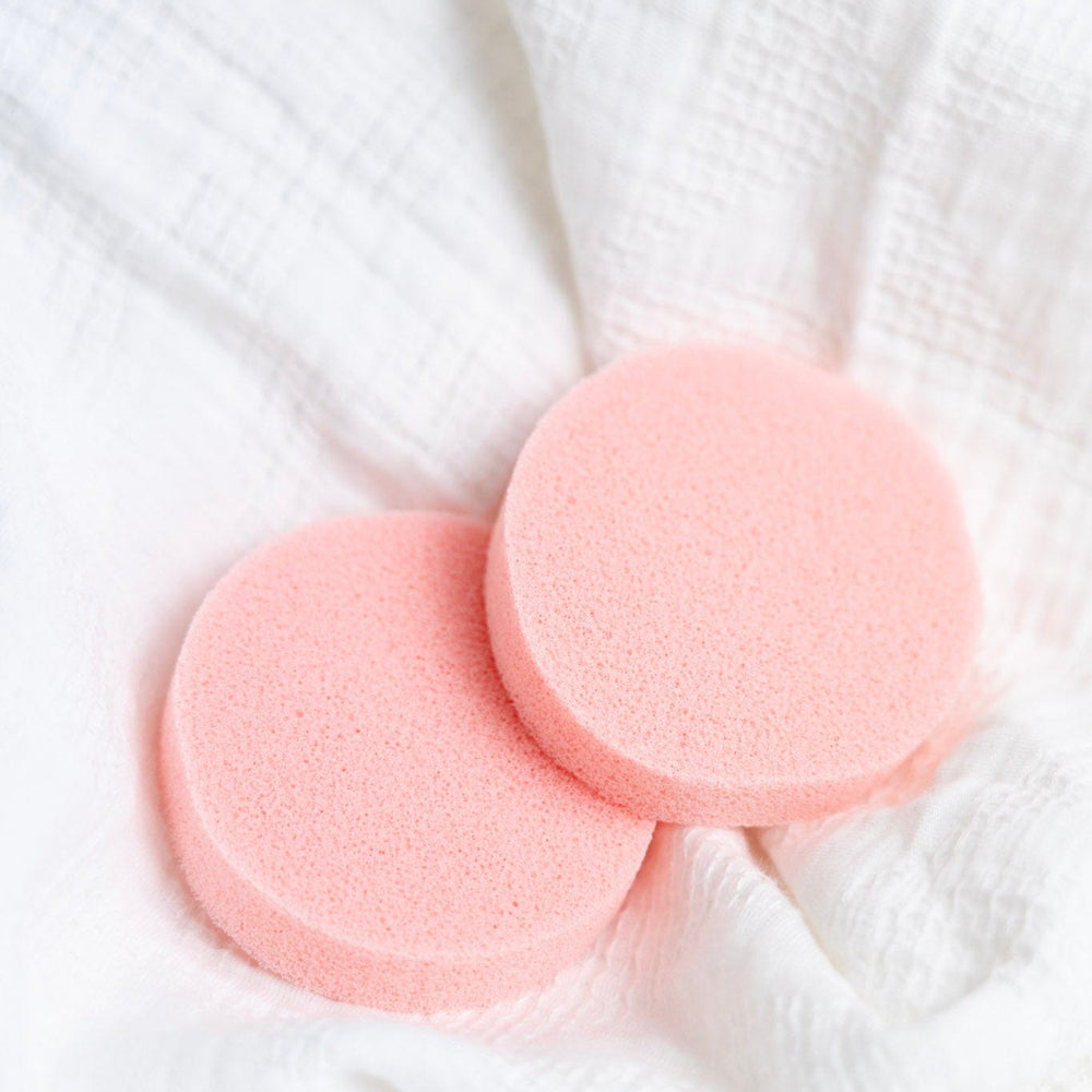 Two pink deodorant removers on a white textured fabric background
