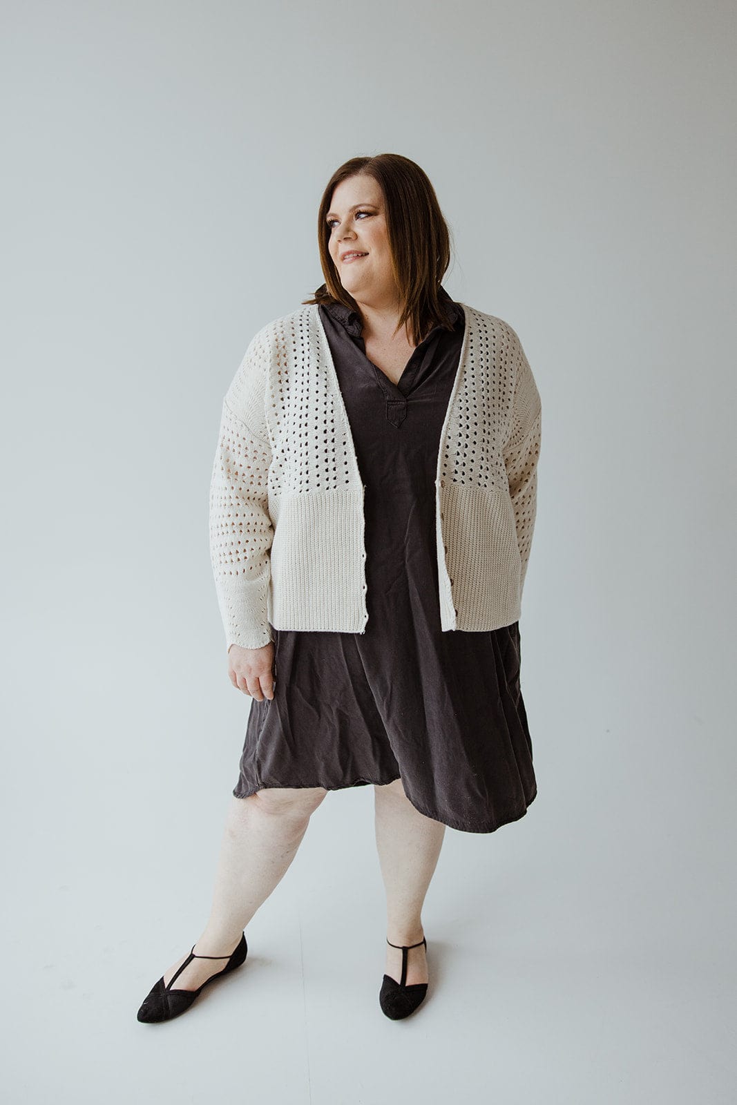 A person stands against a plain background, wearing a dark dress, black shoes, and an **Open Weave Knit Cardigan** by **Love Marlow**, featuring wooden buttons.