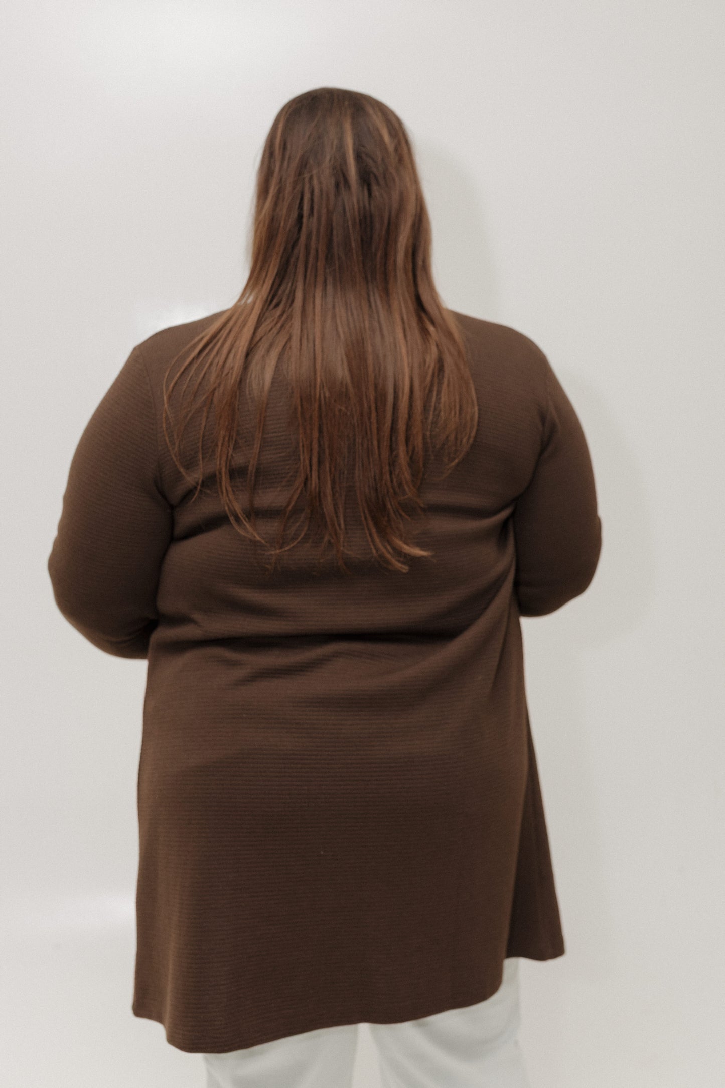Person wearing a brown coat from behind on a white background