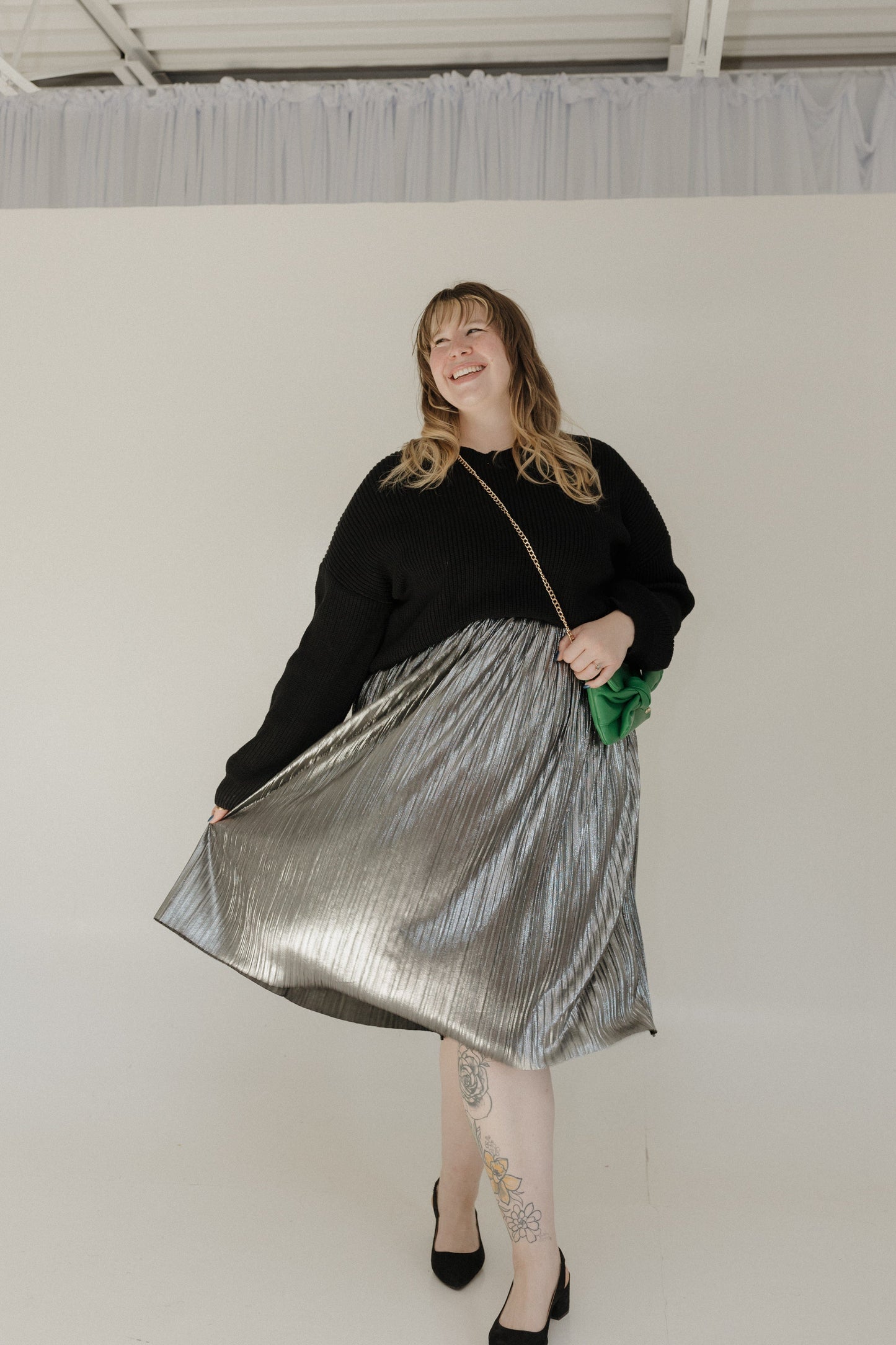 Woman wearing a black top and silver skirt with a white background