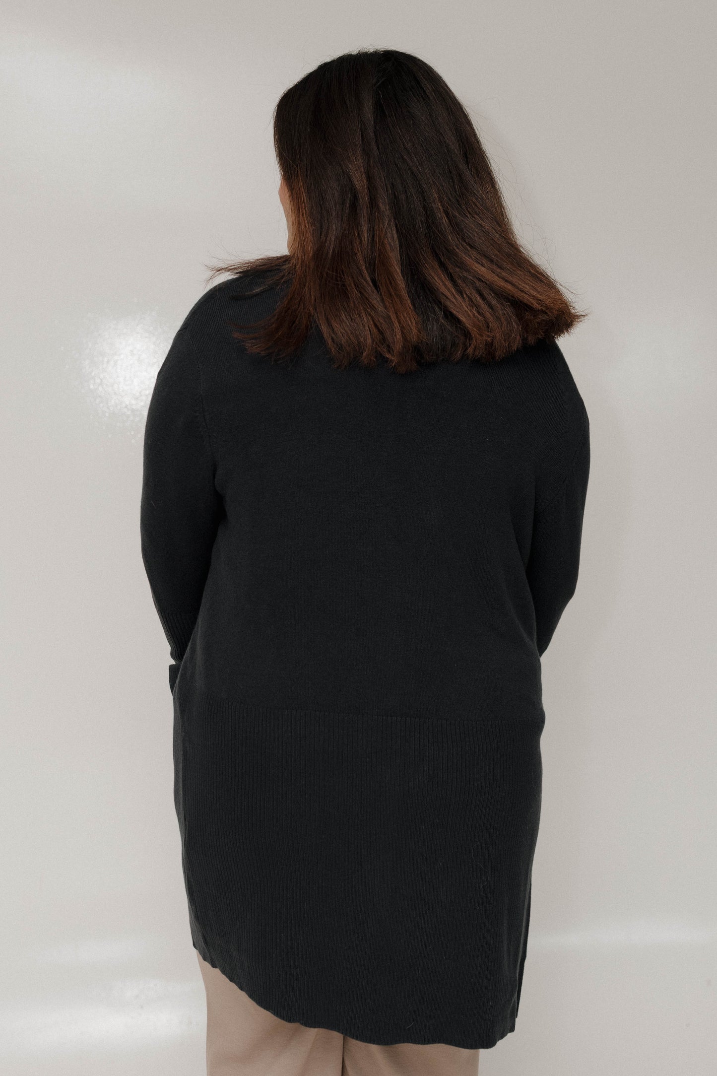 Person wearing a black coat against a white background