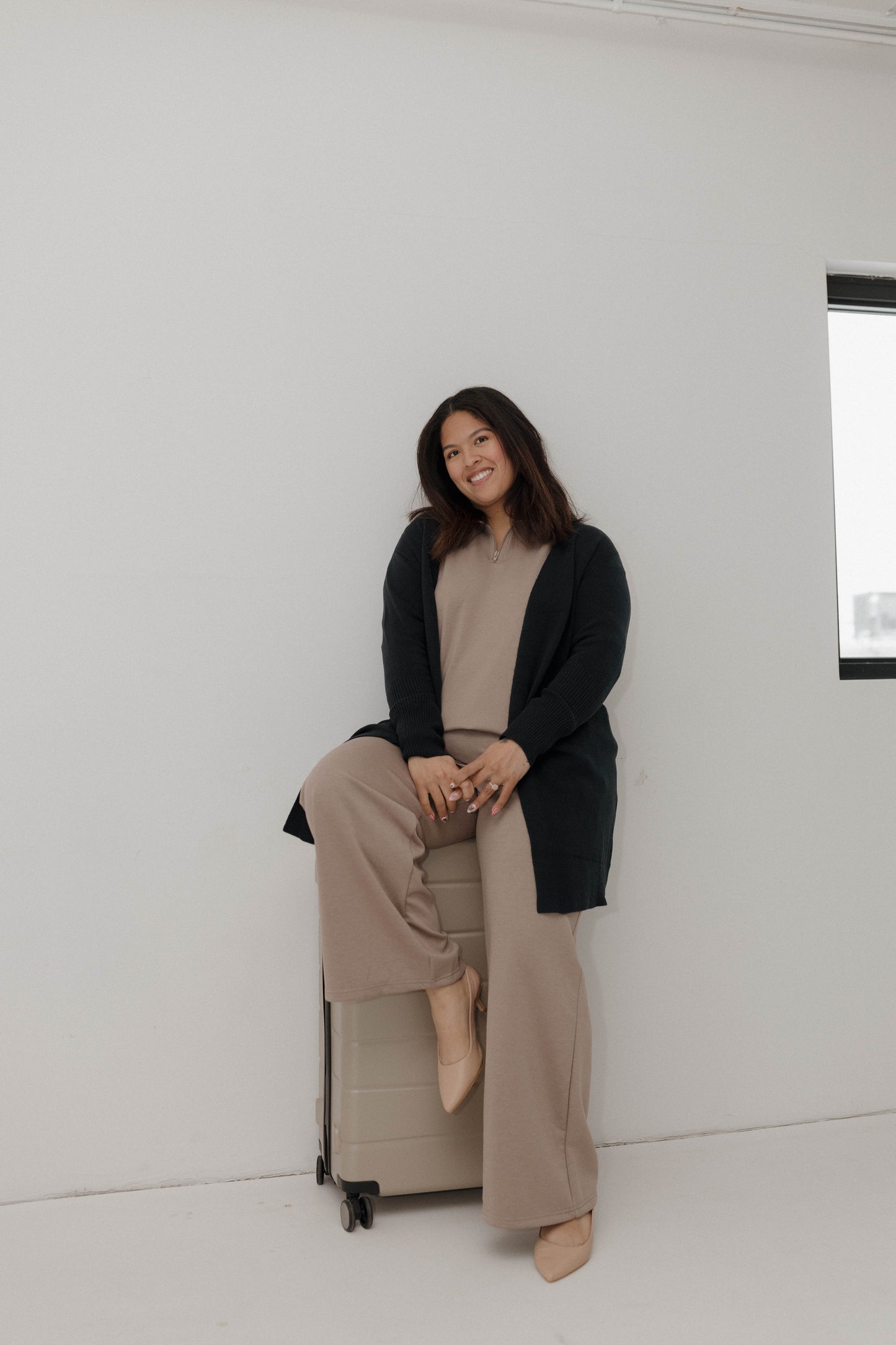 Woman sitting on a box against a white wall