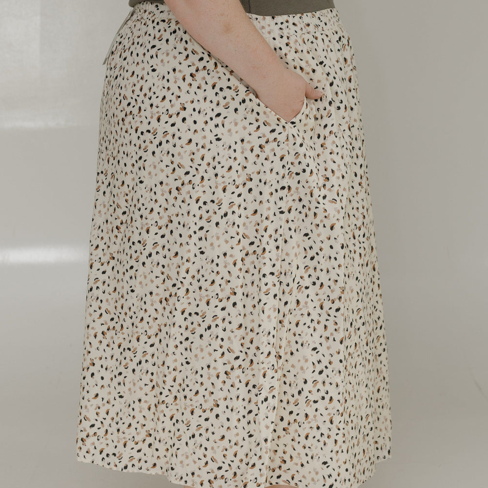 Person wearing a floral skirt and white shoes on a plain background