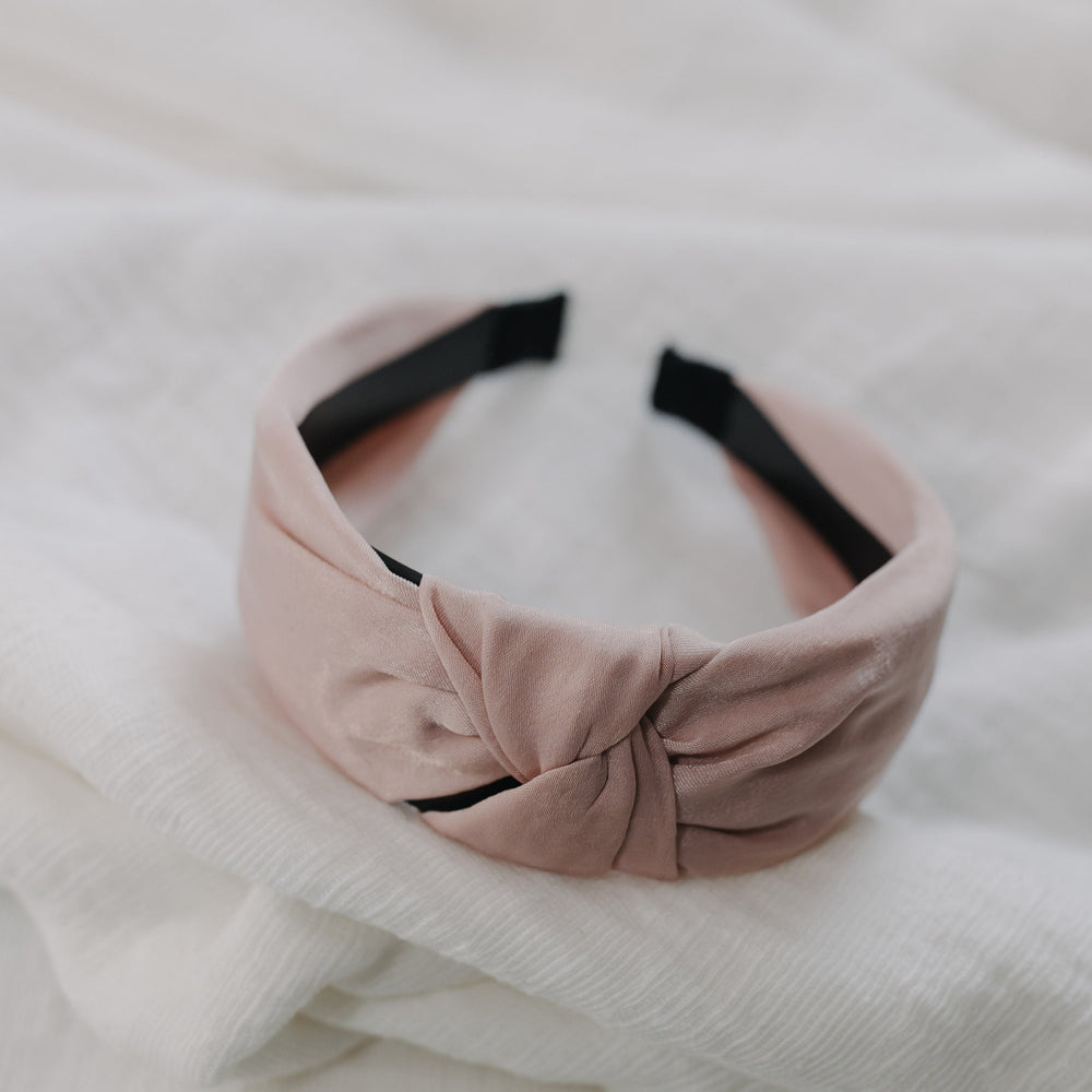 Pink headband with a knot on a white textured background
