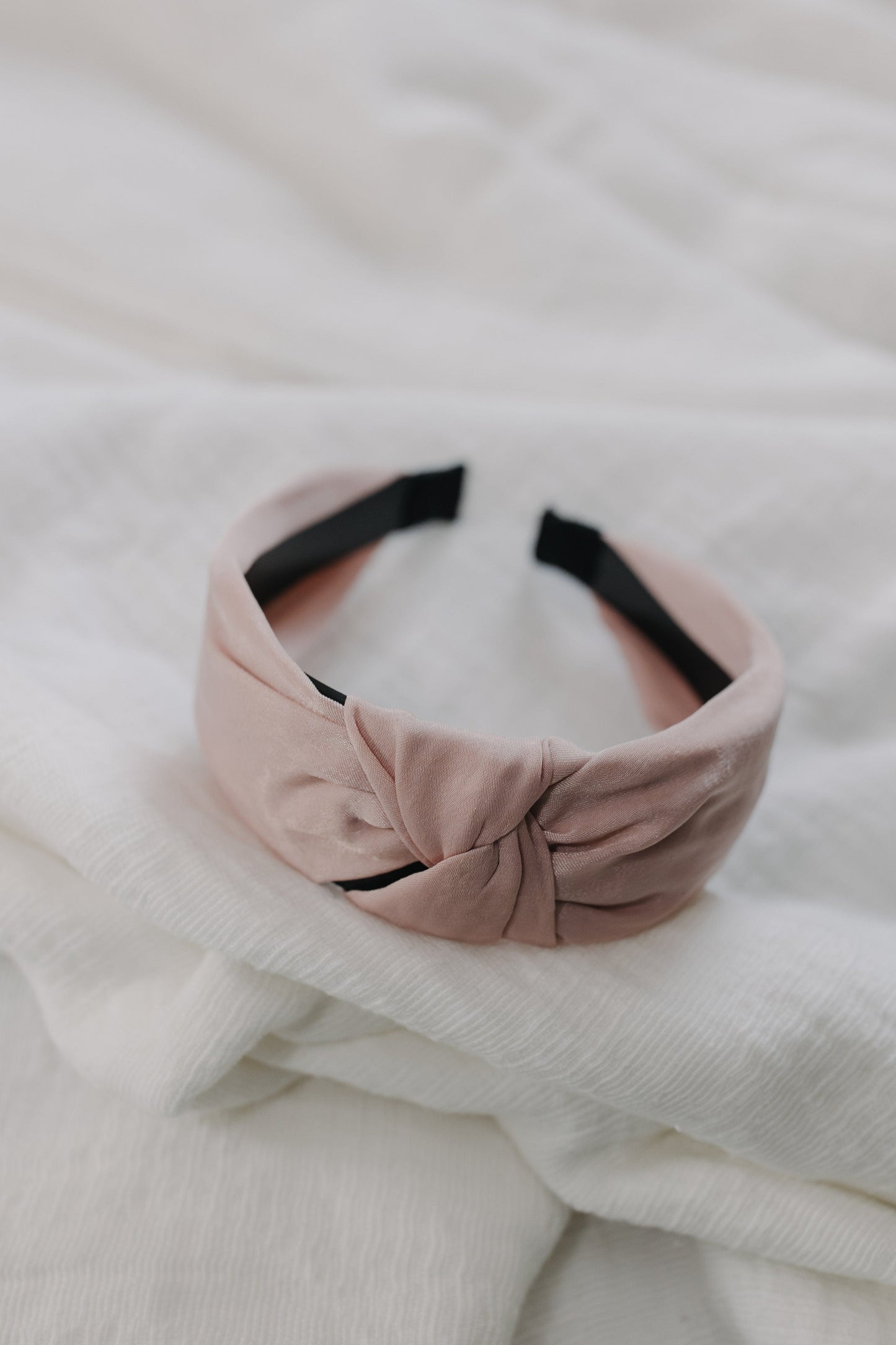 Pink headband with a knot on a white textured background