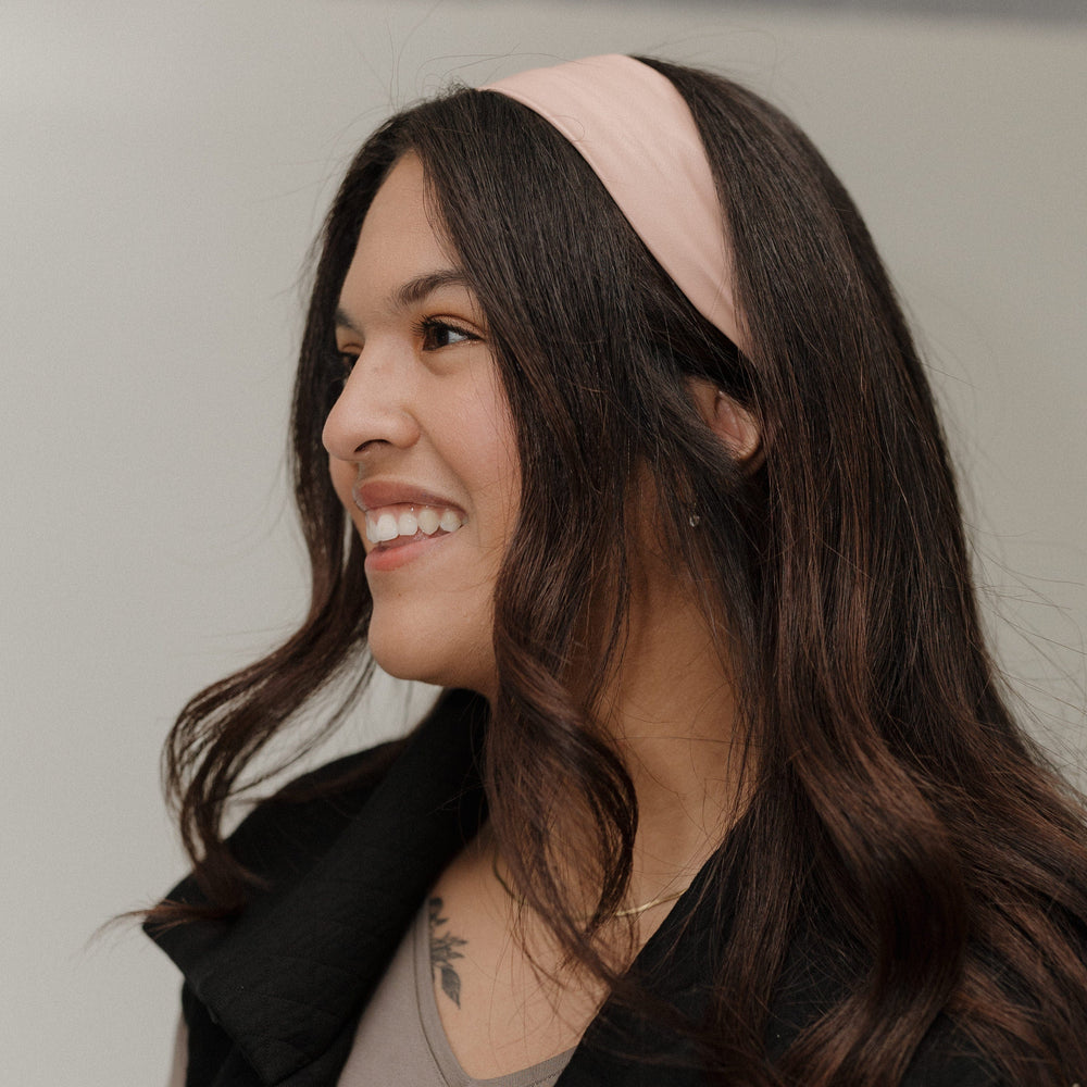 Woman wearing a pink headband with a neutral background