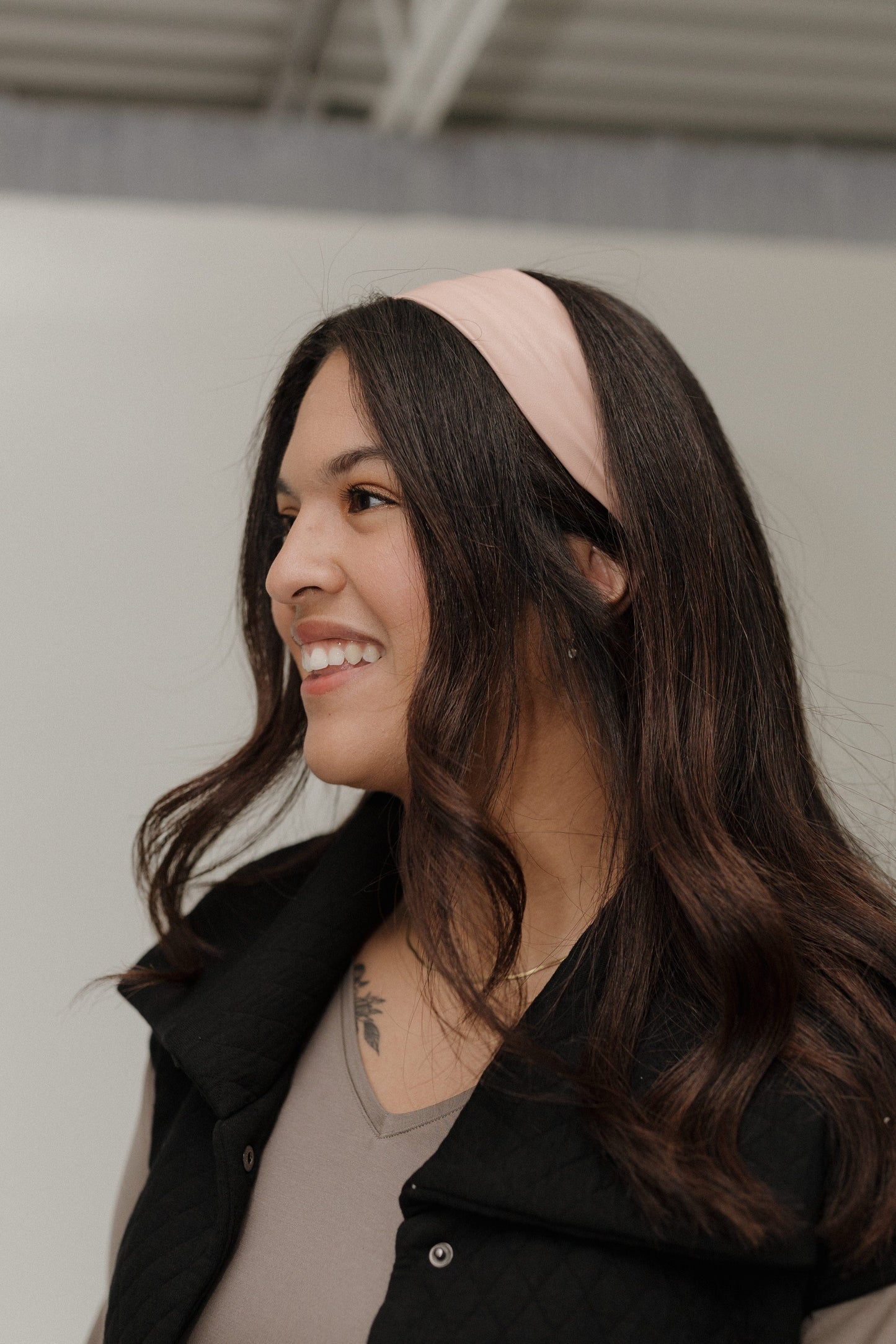 Woman wearing a pink headband with a neutral background