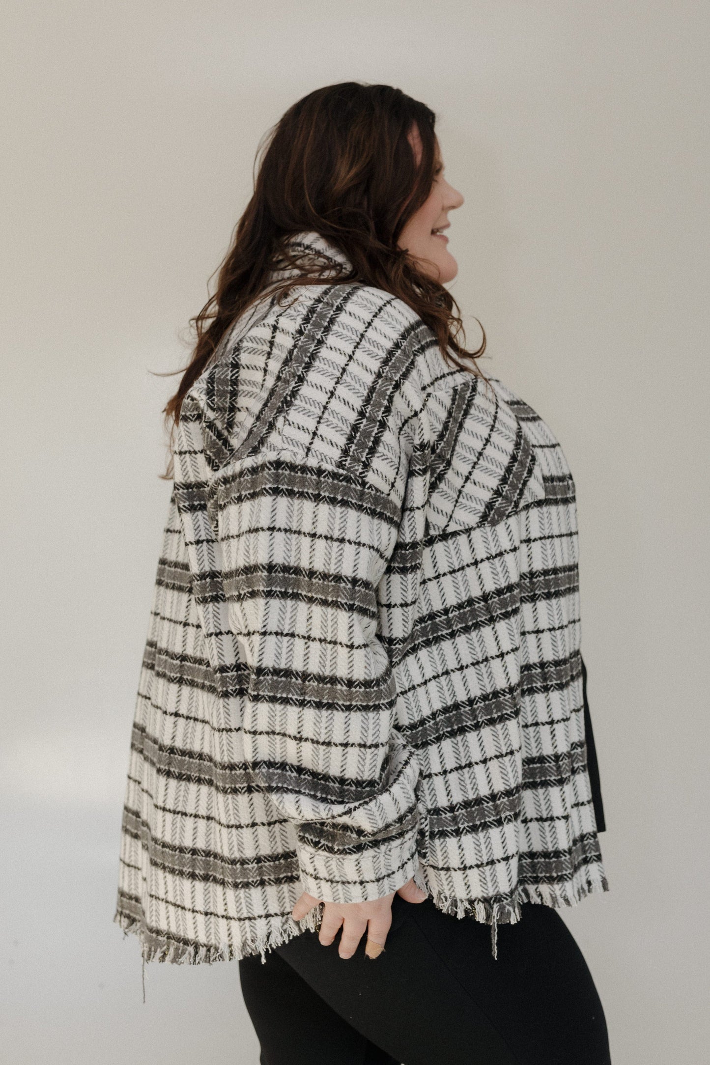 Woman wearing a plaid jacket with a neutral background