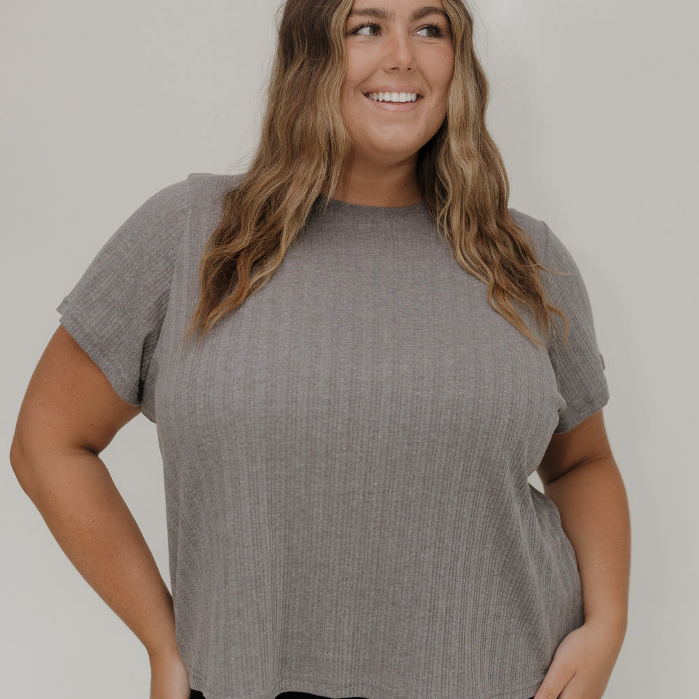 Woman wearing a gray short-sleeve top against a white background