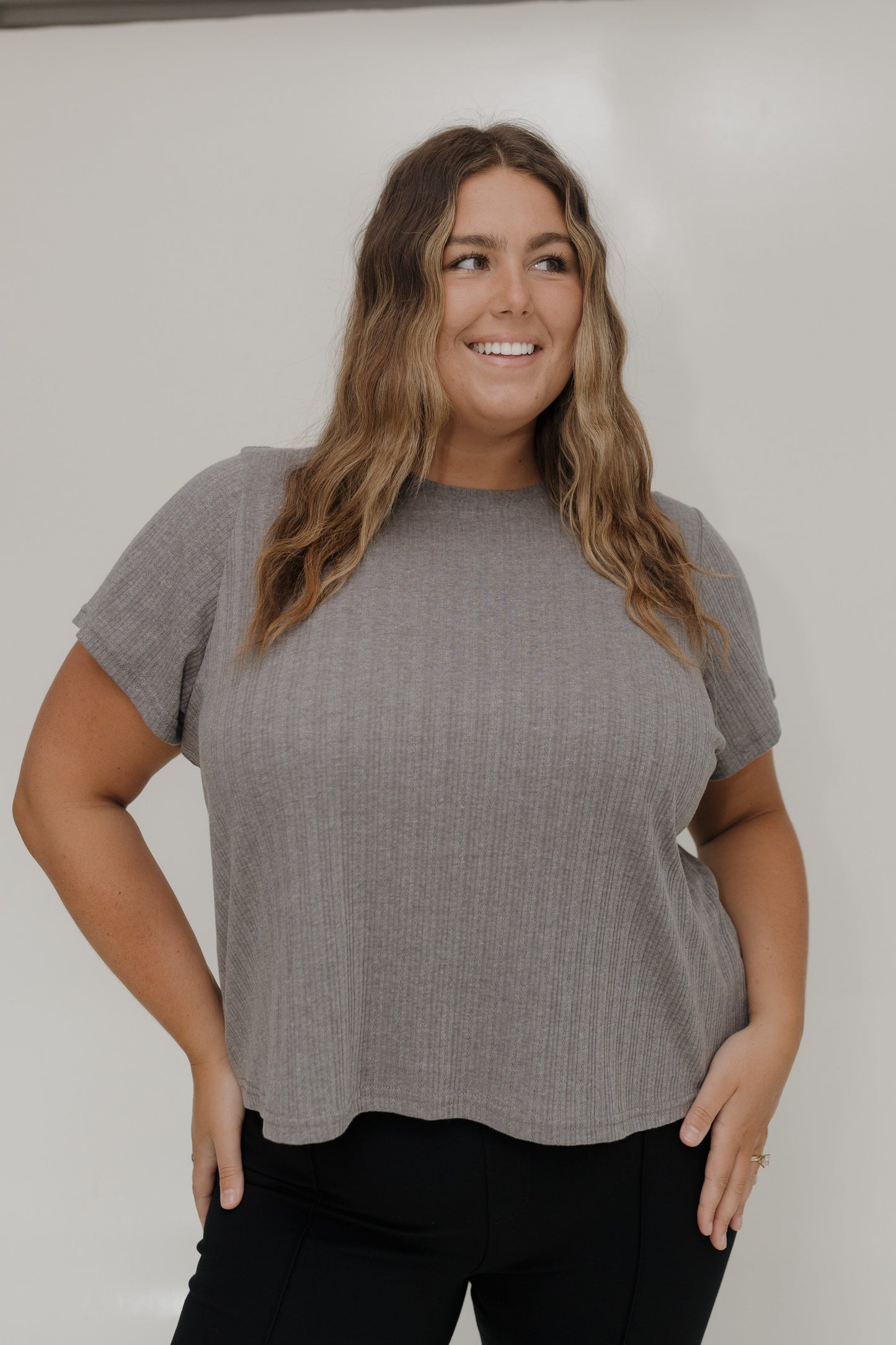 Woman wearing a gray short-sleeve top against a white background