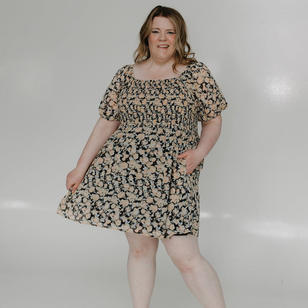 Woman wearing a patterned dress standing against a white background