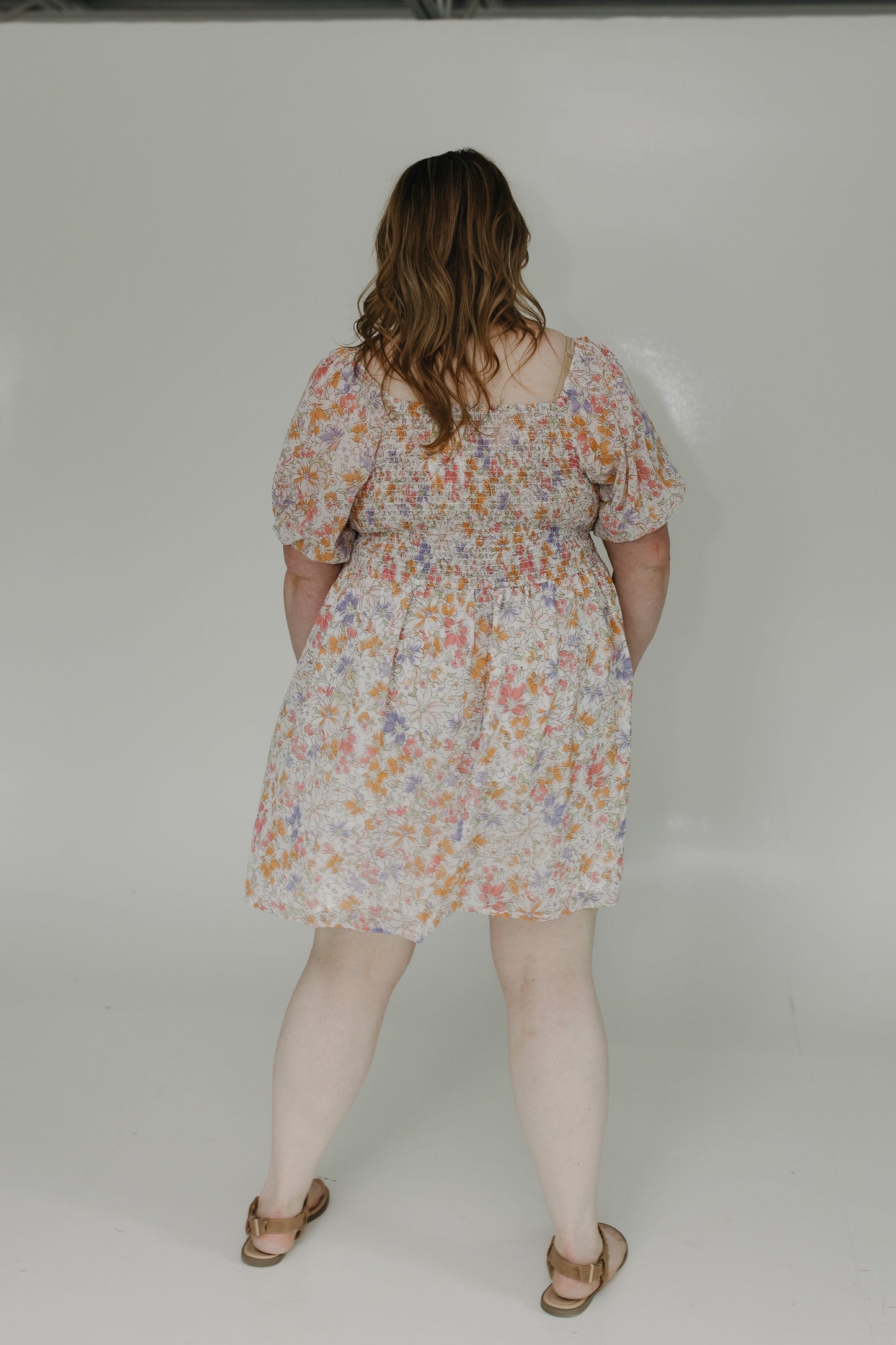 Person wearing a floral dress on a plain background
